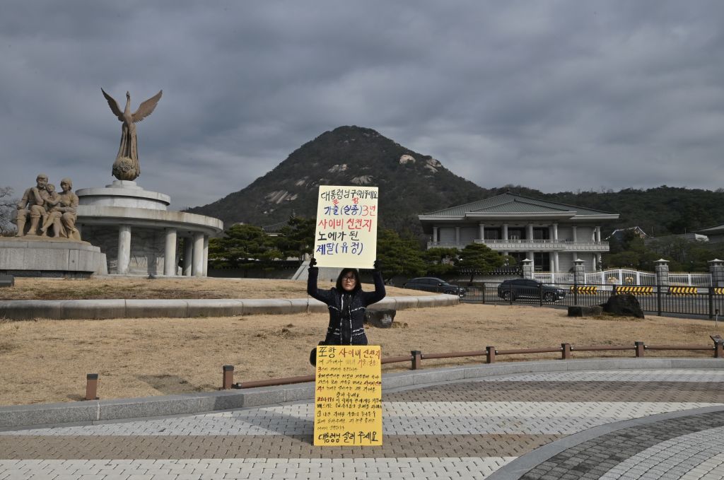 A mother of a Shincheonji Church of Jesus follower holds a placard reading 