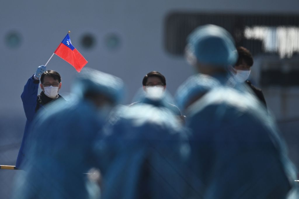 A man holds a Taiwan flag as passengers disembark from the Diamond Princess cruise ship due to fears of COVID-19 in Yokohama, Japan on Feb. 21, 2020. (Philip Fong—AFP/Getty Images)