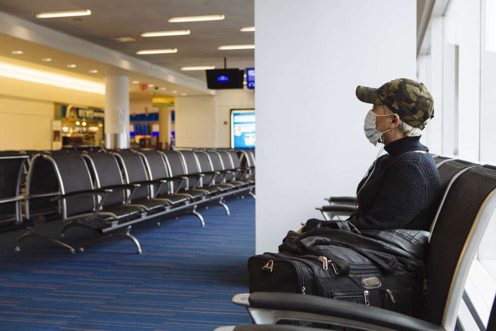 A traveler wearing a protective mask sits at a gate in Terminal 5 at John F. Kennedy International Airport (JFK) in New York, U.S., on Thursday, April 9, 2020. (Angus Mordant–Bloomberg/Getty Images)