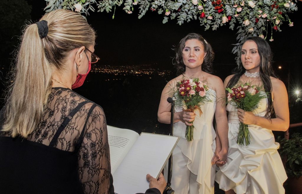 Same-sex newlyweds Alexandra Quiros (C) and Dunia Araya (R) stand before a lawyer during their wedding in Heredia, Costa Rica, on May 26, 2020. (Ezequiel Becerra—AFP via Getty Images)