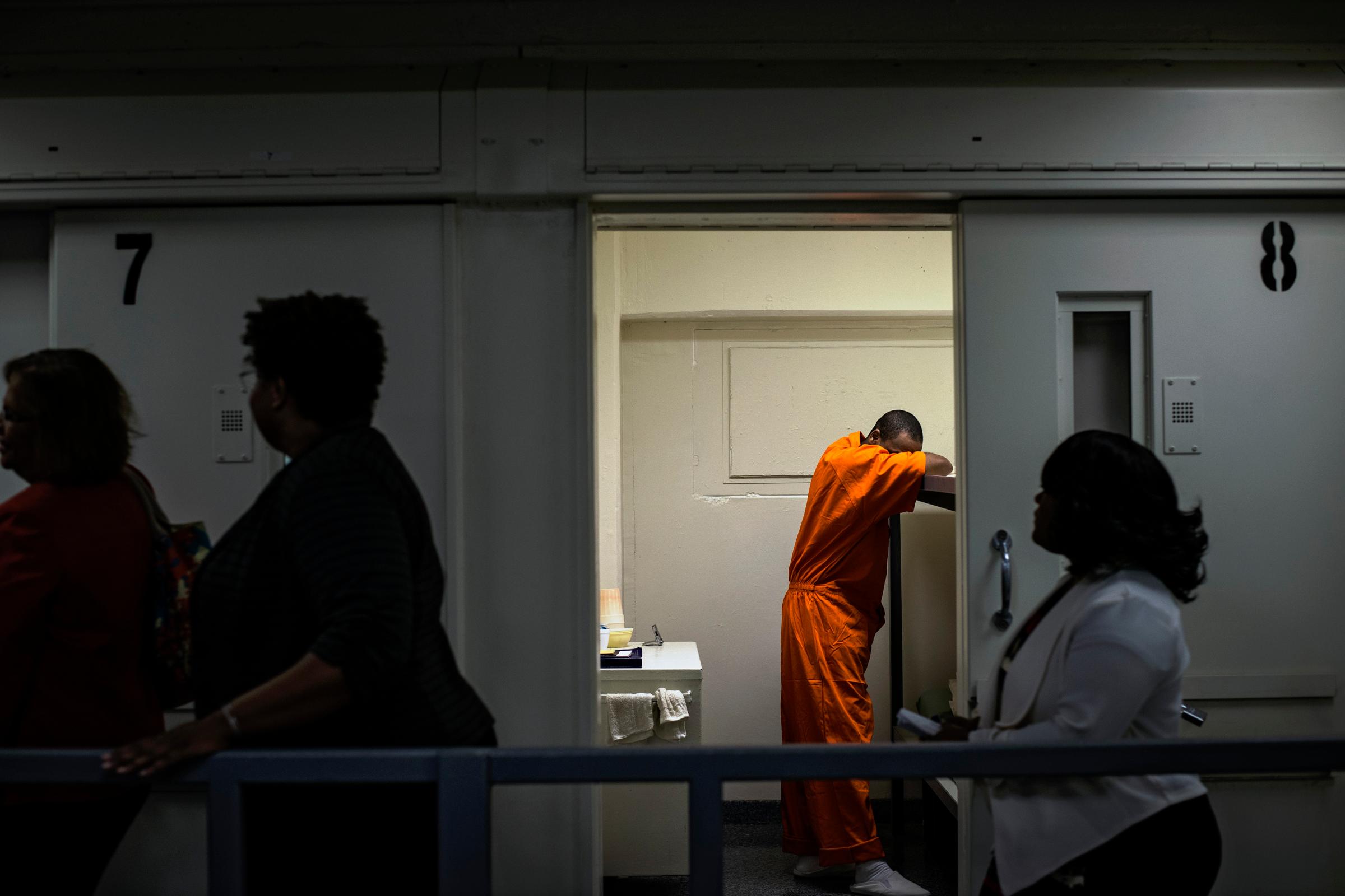 Members of DC Mayor Muriel Bowser's entourage walk past an inmate's cell as she tours DC Central Jail after announcing policy changes to support employment for inmates during and after incarceration in Washington