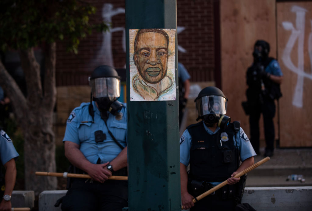 A portrait of George Floyd hangs on a street light pole as police officers stand guard at the Third Police Precinct during a face off with a group of protesters in Minn., Minnesota, May 27, 2020. (Stephen Maturen—Getty Images)