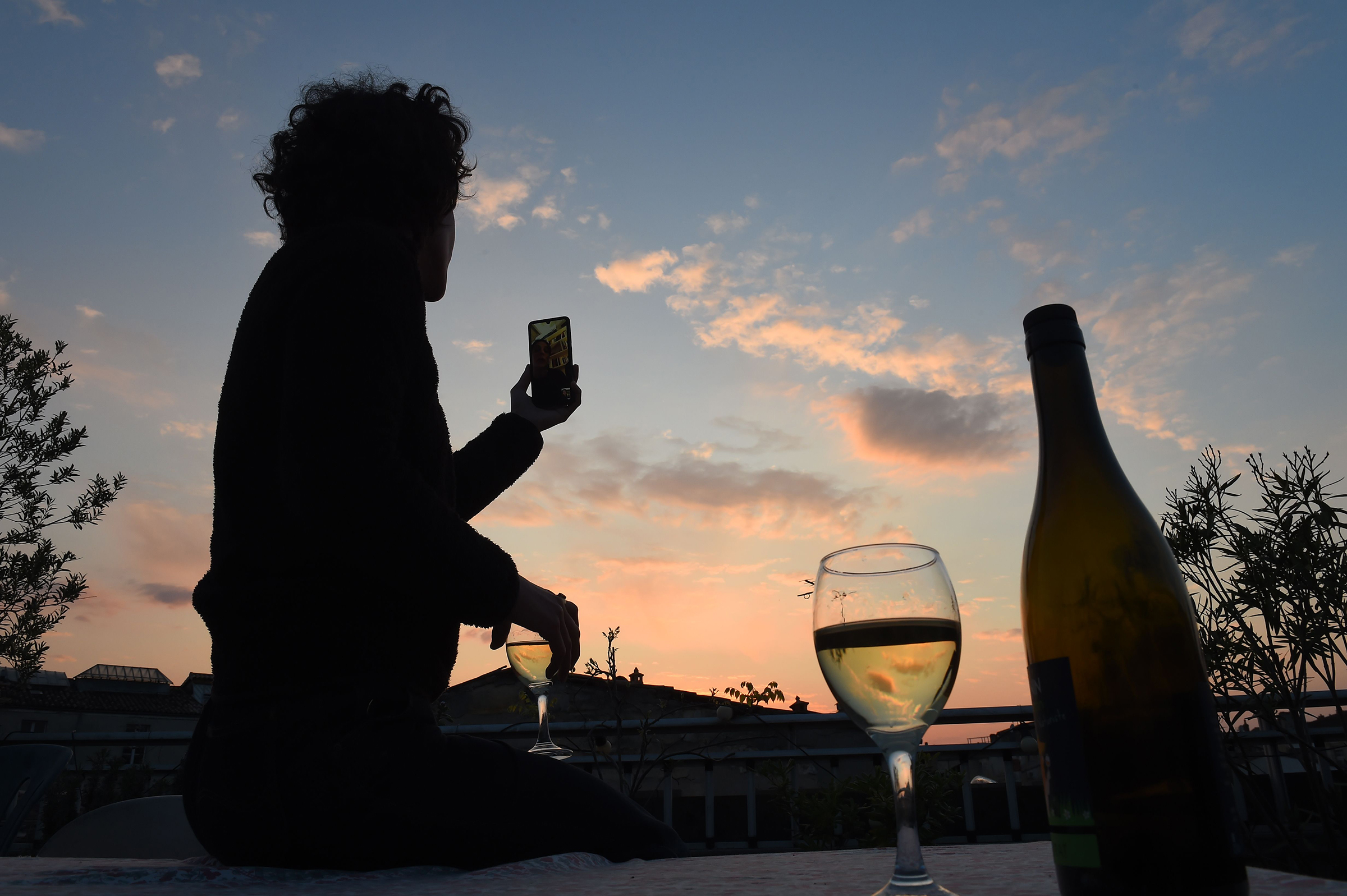 A woman drinks a glass of wine as she speaks and shares a drink with friends via a video call on March 26 in Bordeaux, southwestern France, in the evening on the tenth day of a lockdown aimed at curbing the spread of the COVID-19 in France (Nicolas Tucat—AFP/Getty IMages)