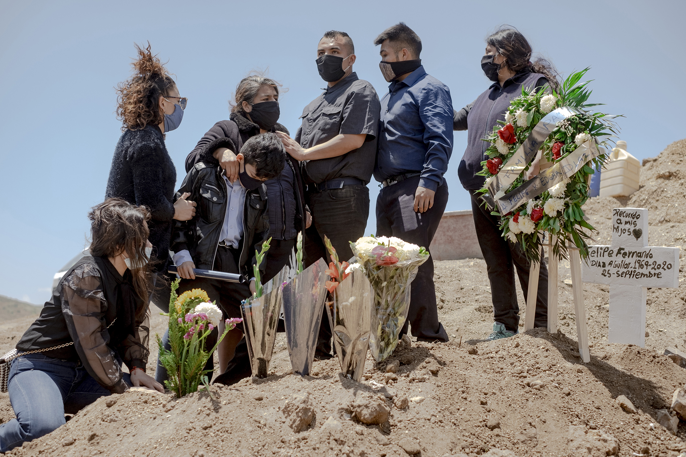 A family wearing protective masks mourns during the burial of a relative who died from coronavirus at Municipal Cemetery No. 13 in Tijuana, Mexico, on May 12.