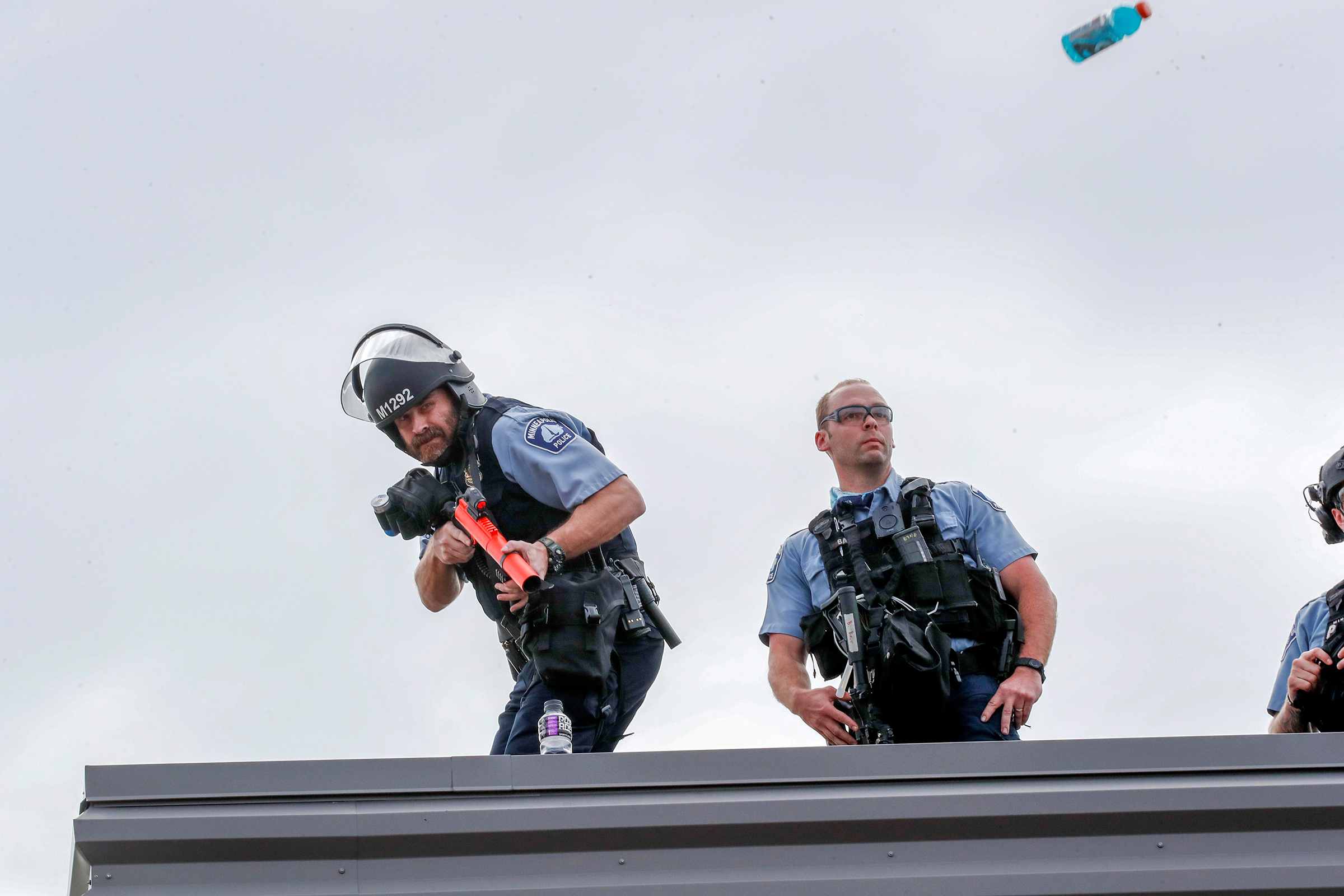 A police officer ducks to avoid a Gatorade bottle thrown by people gathered at the 3rd precinct on May 27.
