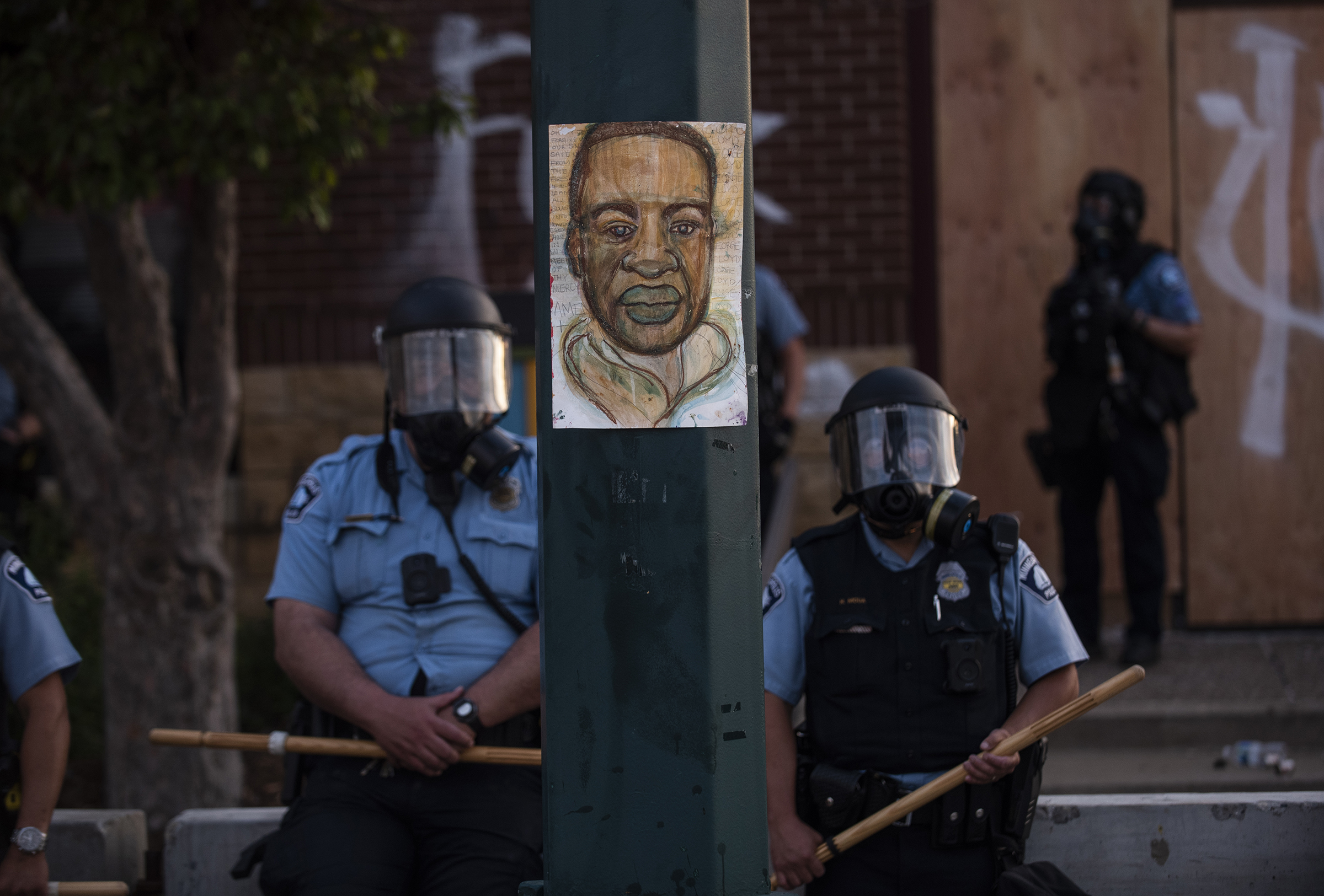 A portrait of George Floyd hangs on a street light pole as police officers stand guard at the 3rd precinct during a face off with protesters on May 27. (Stephen Maturen—Getty Images)