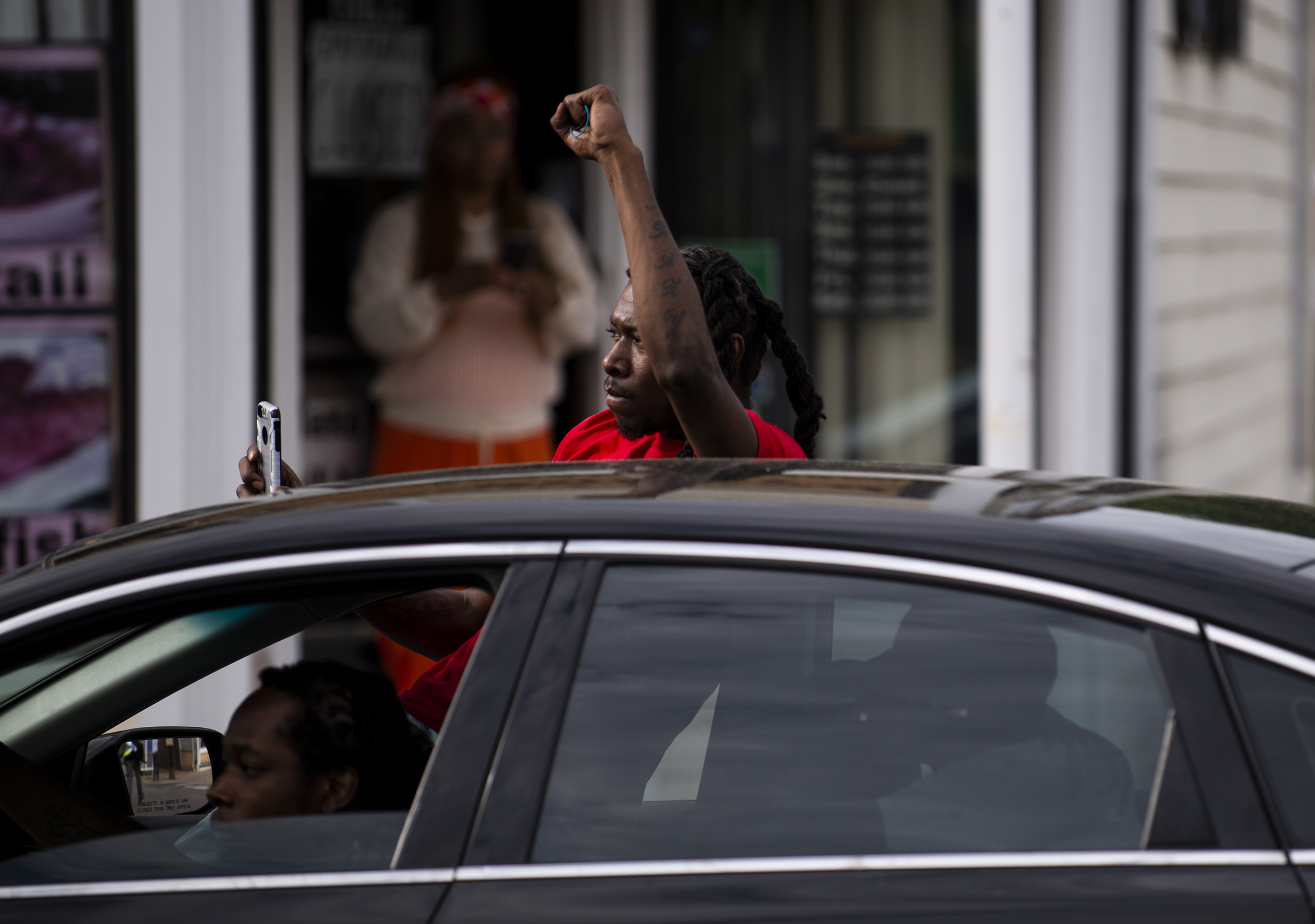 A man leans out of his car and with a raised fist as protesters march by decrying the killing of George Floyd in Minneapolis on May 26, 2020.