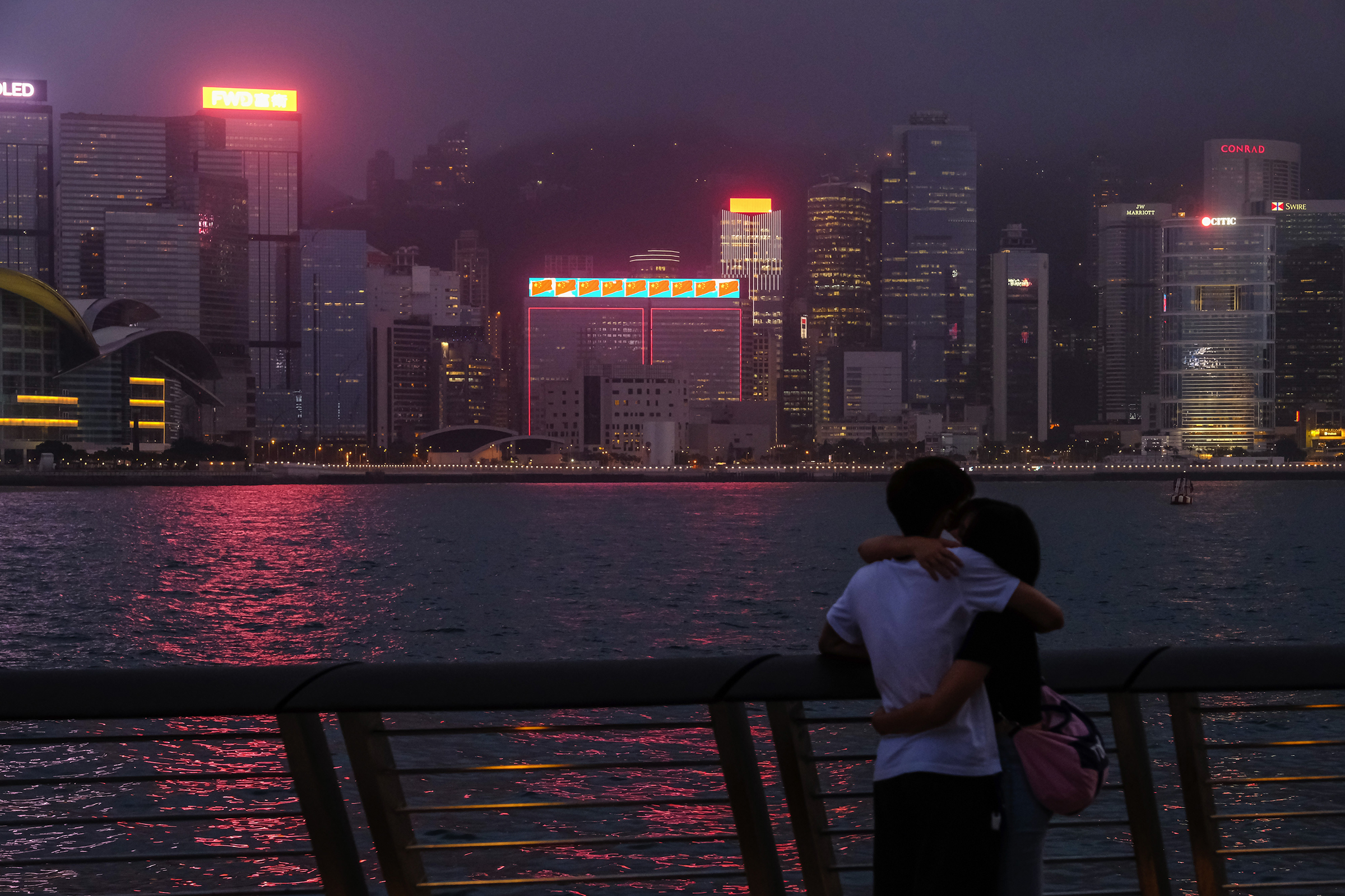 A couple across from illuminated skyscrapers on Victoria Harbor in Hong Kong on May 28, 2020.