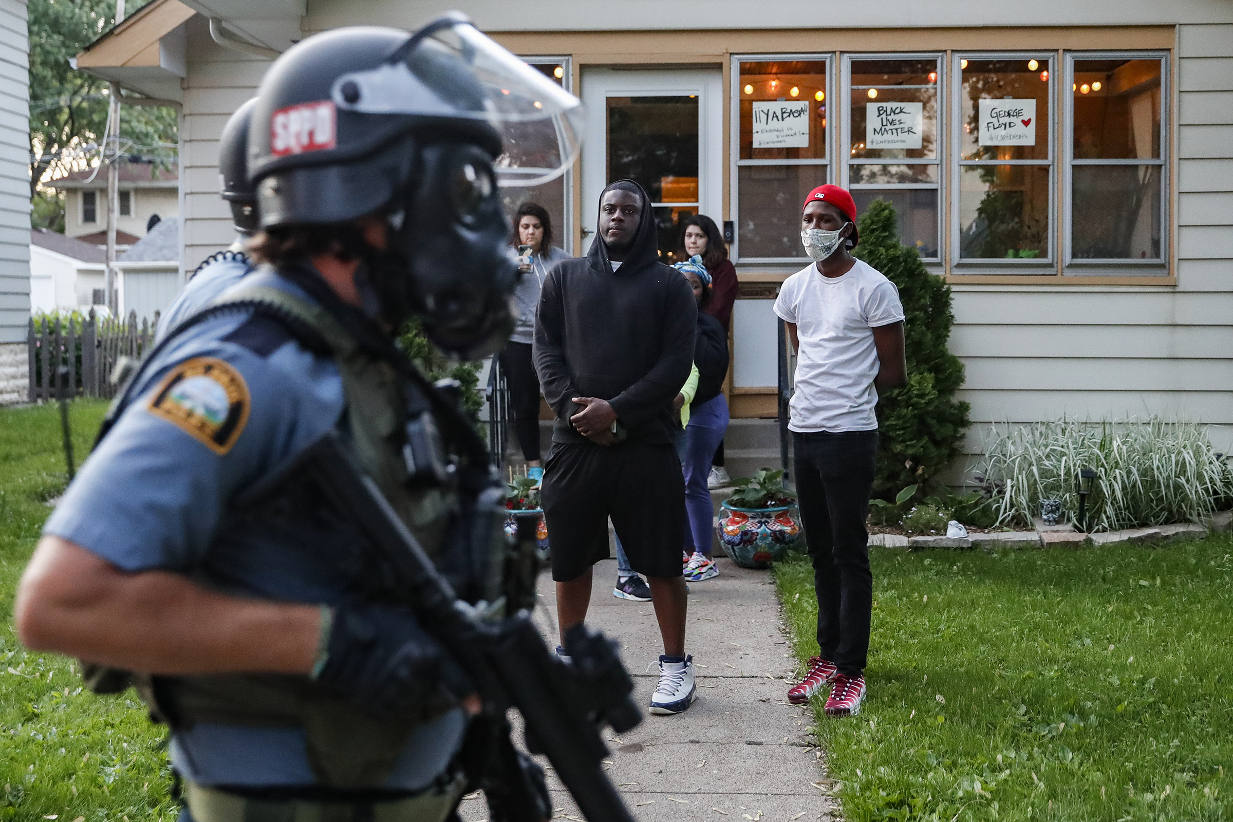 Protesters watch as police in riot gear walk down a residential street in St. Paul, Minn., on May 28. (John Minchillo—AP)
