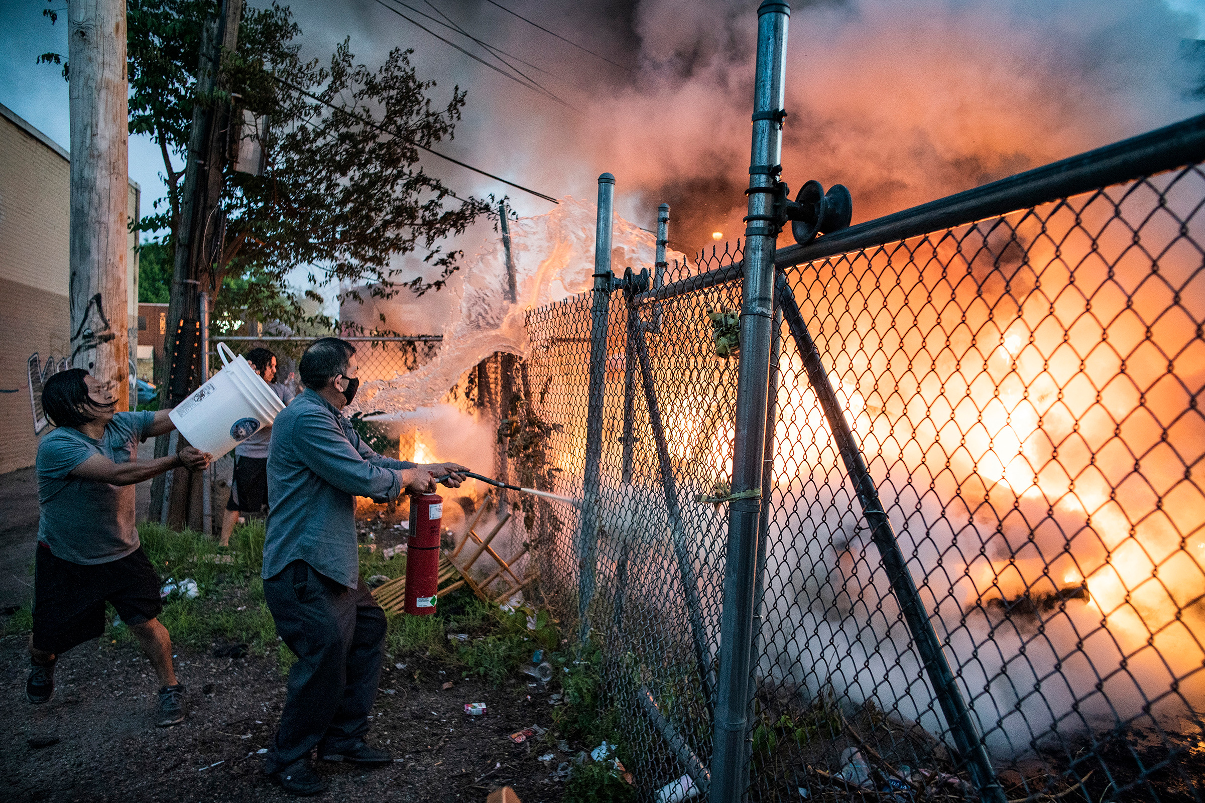 Residents put out a car fire near Lake Street in Minneapolis, Minn., on May 29, 2020. As peaceful demonstrations turned increasingly violent by some protestors, Mayor Jacob Frey ordered a citywide curfew at 8 p.m. local time. (Richard Tsong-Taatarii—Star Tribune/AP)