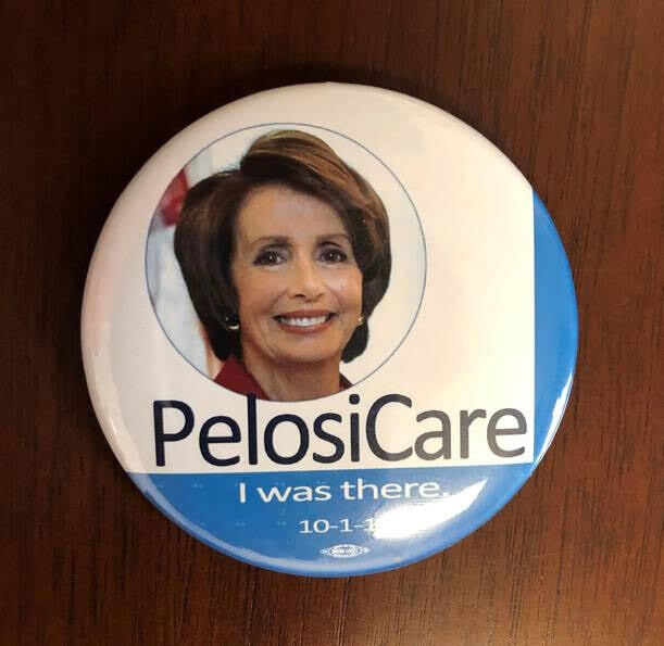 A button with Nancy Pelosi's face on it and the words "Pelosi Care" and "I was there"
