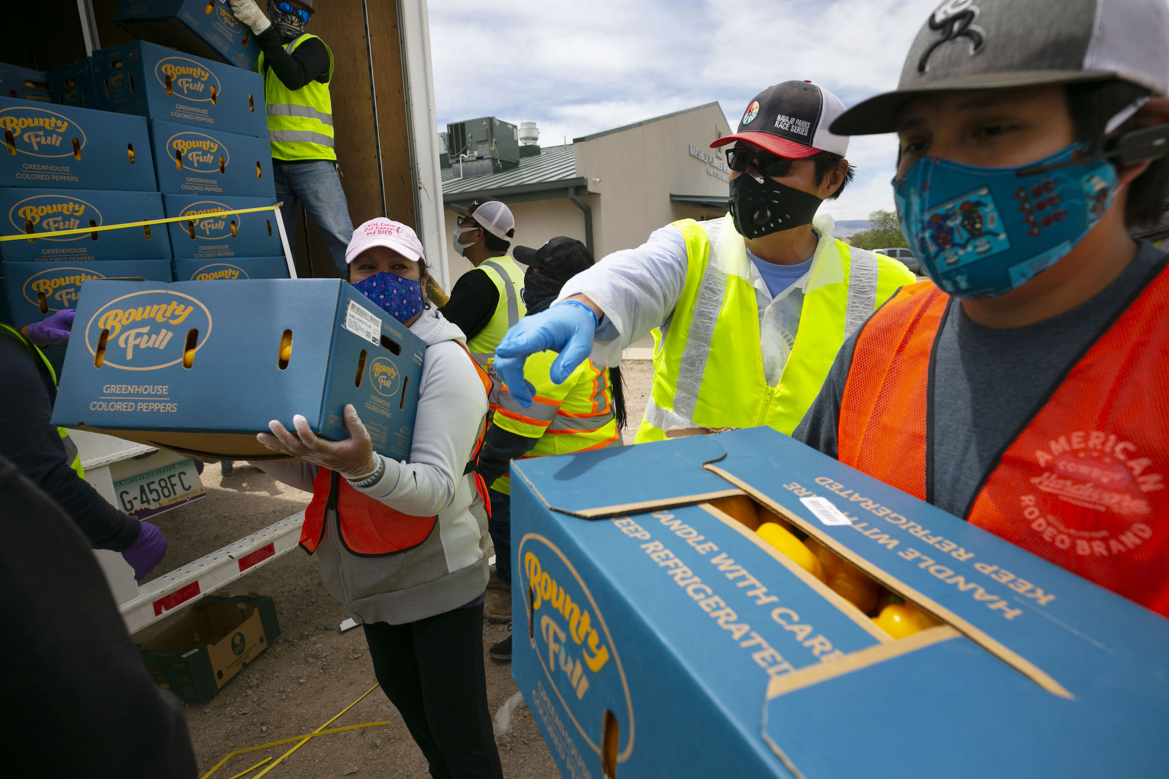 Navajo Nation President Jonathan Nez, center, and Isaiah Tsosie, right, an office specialist with the Coyote Canyon chapter, move food for distribution in Coyote Canyon, N.M., on the Navajo Nation on May 15, 2020.