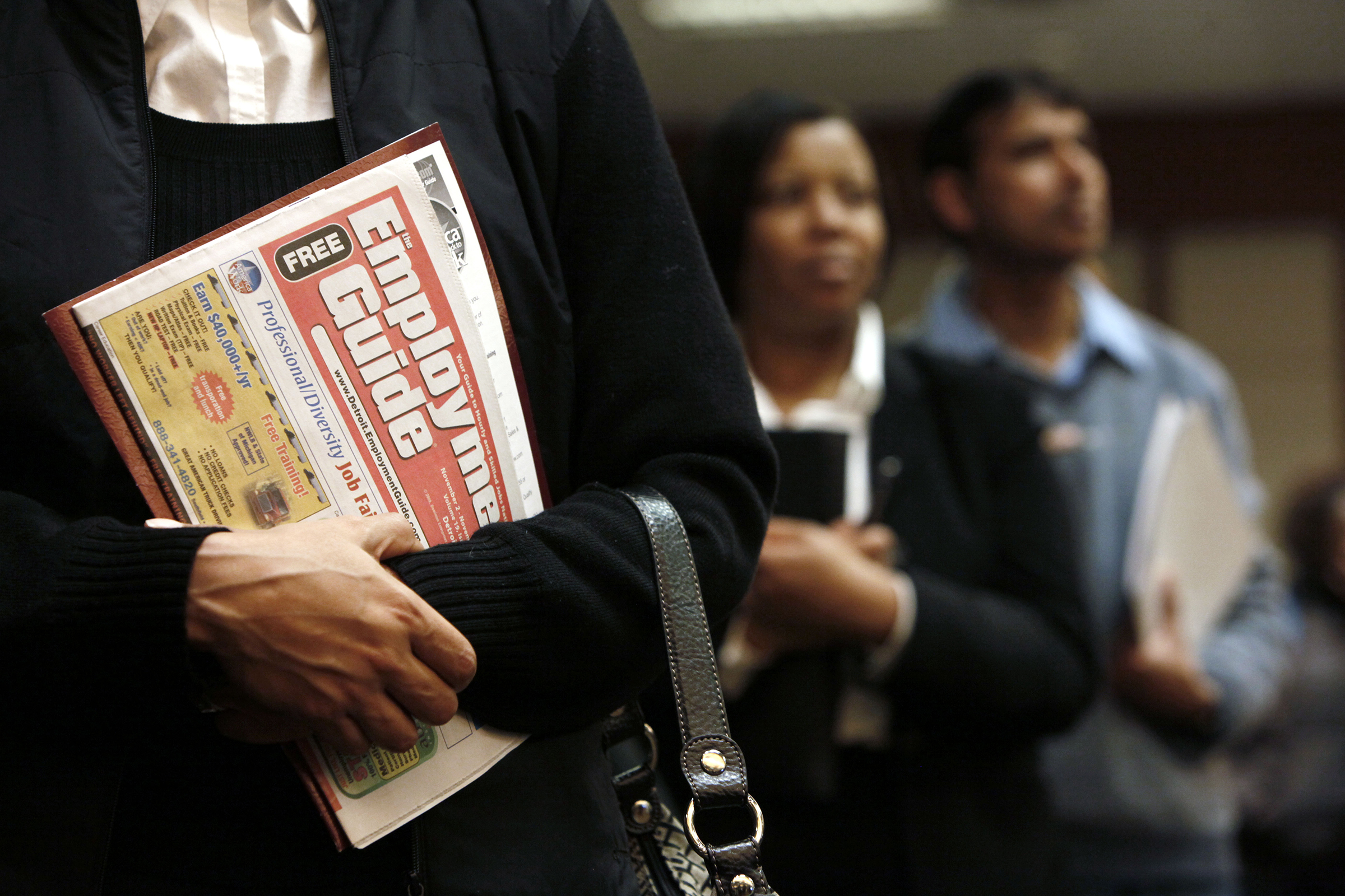 A woman holds an employment guide standing in line while attending a job fair in Livonia, Michigan, on Nov. 4, 2009. (Paul Sancya—AP)