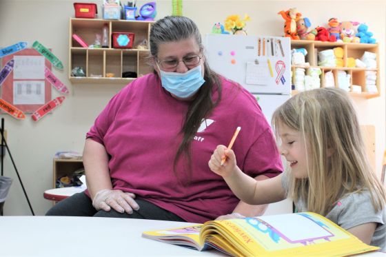 YMCA childcare provider Darlene Mount is pictured helping a child
