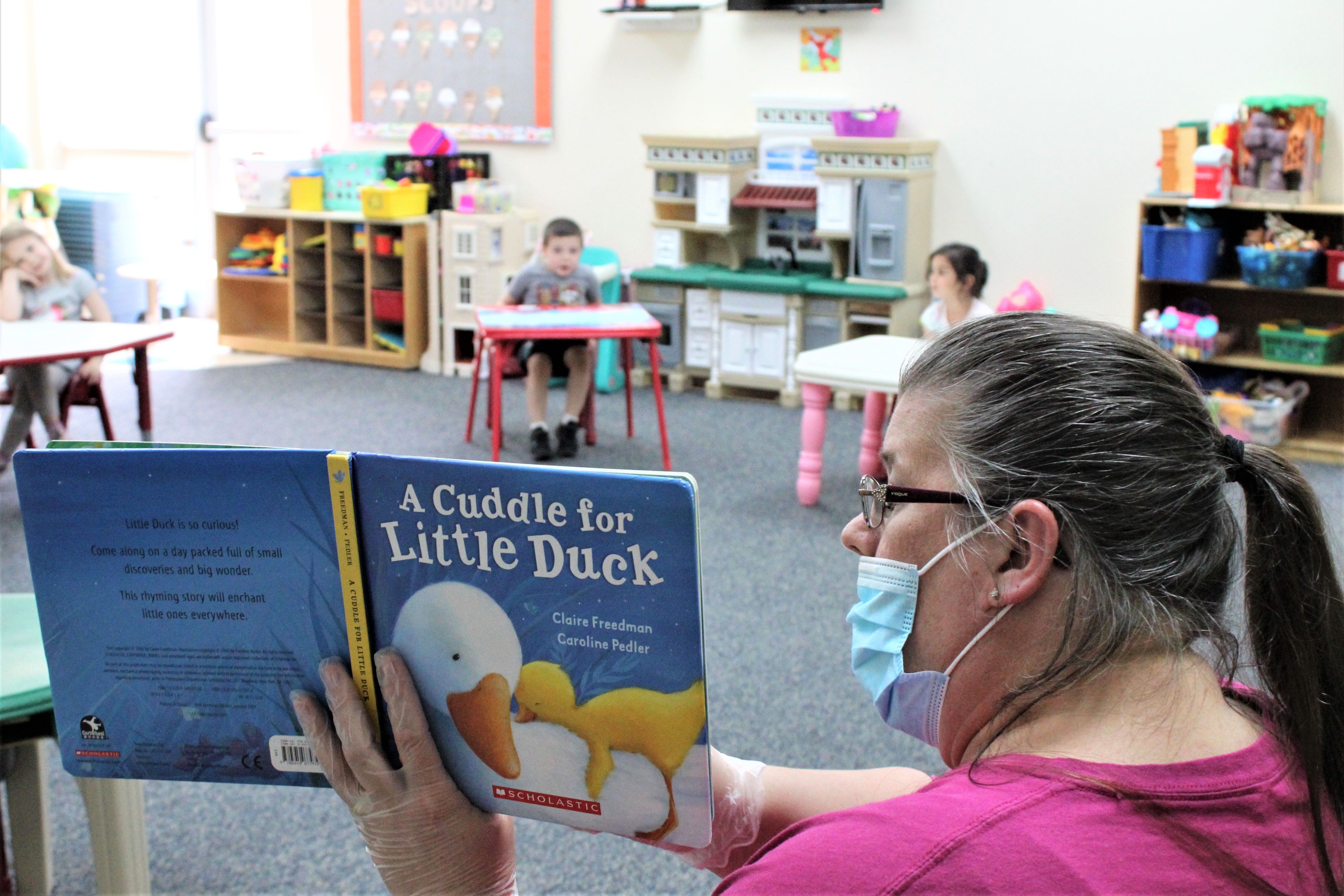 Daycare provider Darlene Mount reads a book to children at a New Jersey YMCA during the ongoing COVID-19 pandemic. The children are in a modified circle that allows for proper social distancing. (Courtesy of Andrea Plaza)