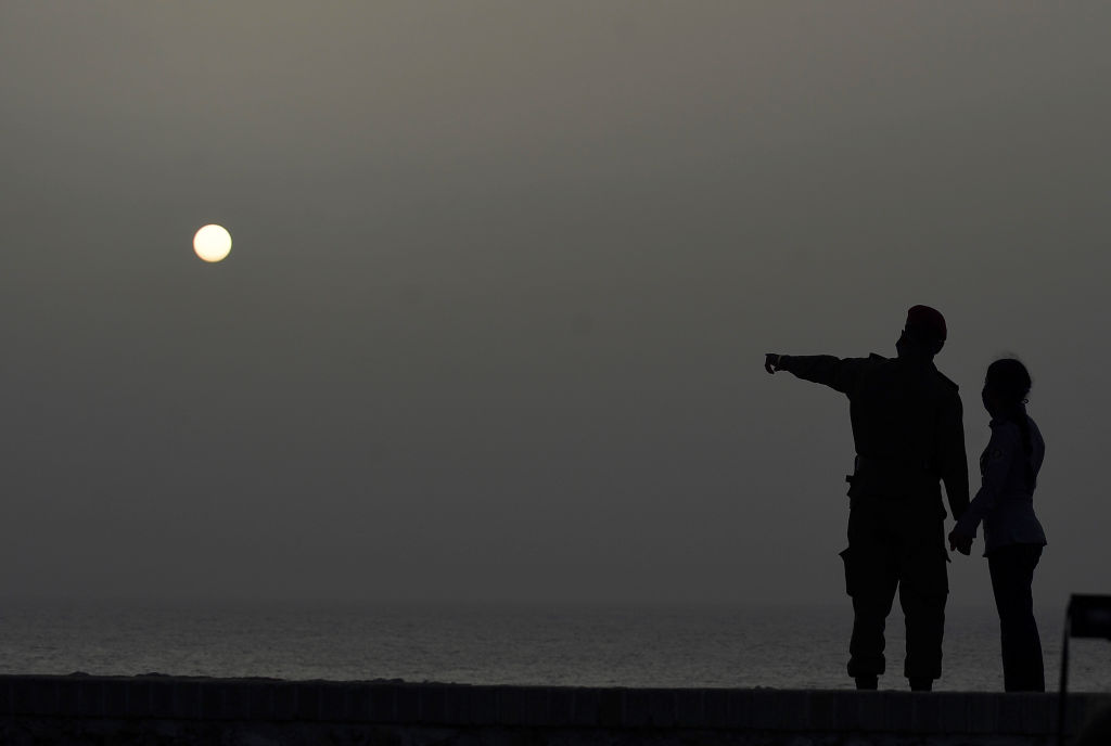 A couple look at the sea as a vast cloud of Sahara dust is blanketing the city of Havana on June 24, 2020. A massive cloud of Saharan dust darkened much of Cuba on Wednesday and began to affect air quality in Florida, sparking warnings to people with respiratory illnesses to stay home. (Yamil Lage—Getty Images)