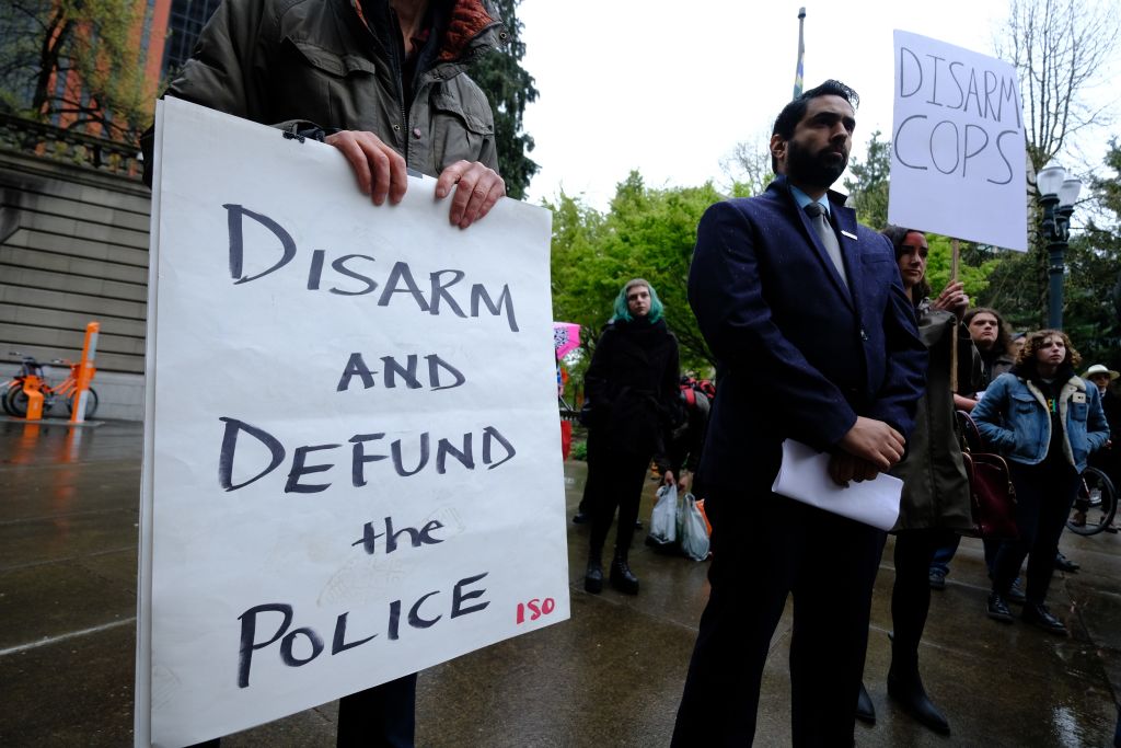 A protester holds a sign reading "Disarm And Defund The Police" during a protest against fatal police shootings in Portland, Oregon, United States on April 11, 2018. John Andrew Elifritz, 48, was fatally shot by police after he reportedly fled from a stolen car and burst into a homeless shelter at the start of an alcoholics anonymous meeting last Saturday. (Alex Milan Tracy—Getty)