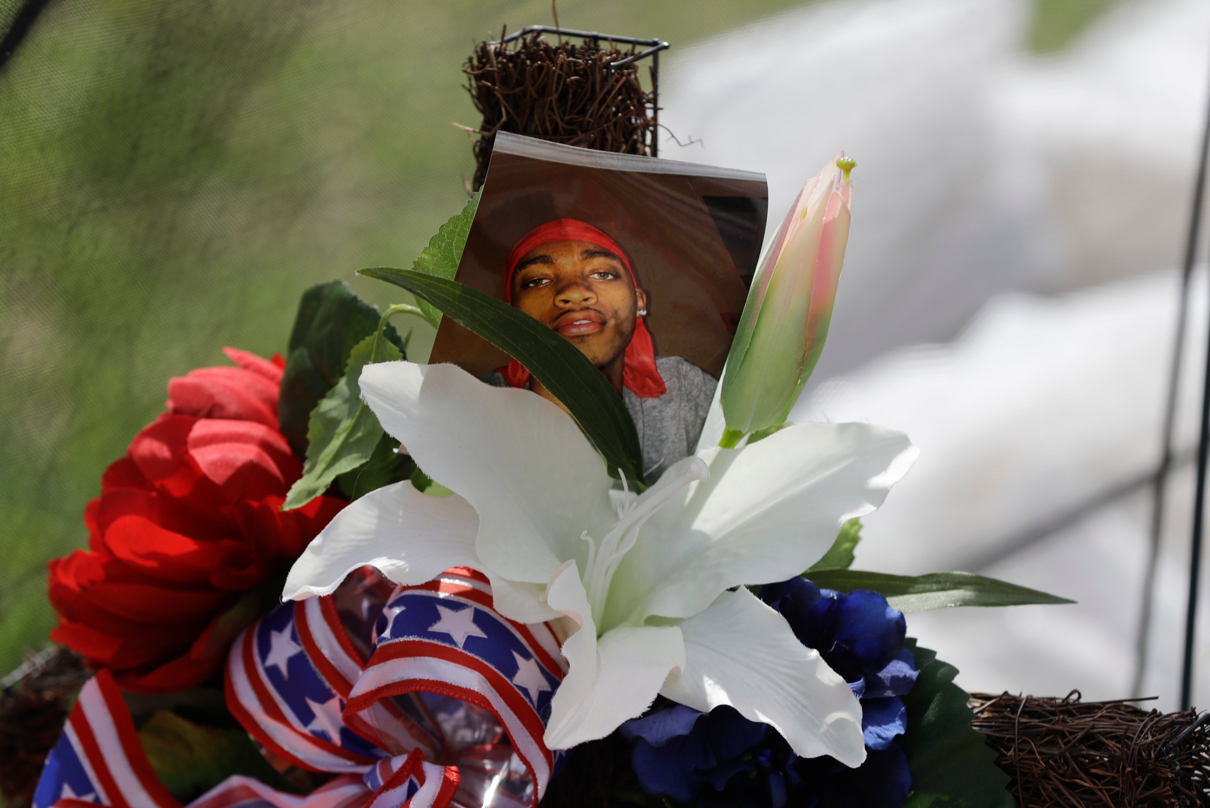 A photo of Dreasjon "Sean" Reed is placed in a memorial before a news conference
