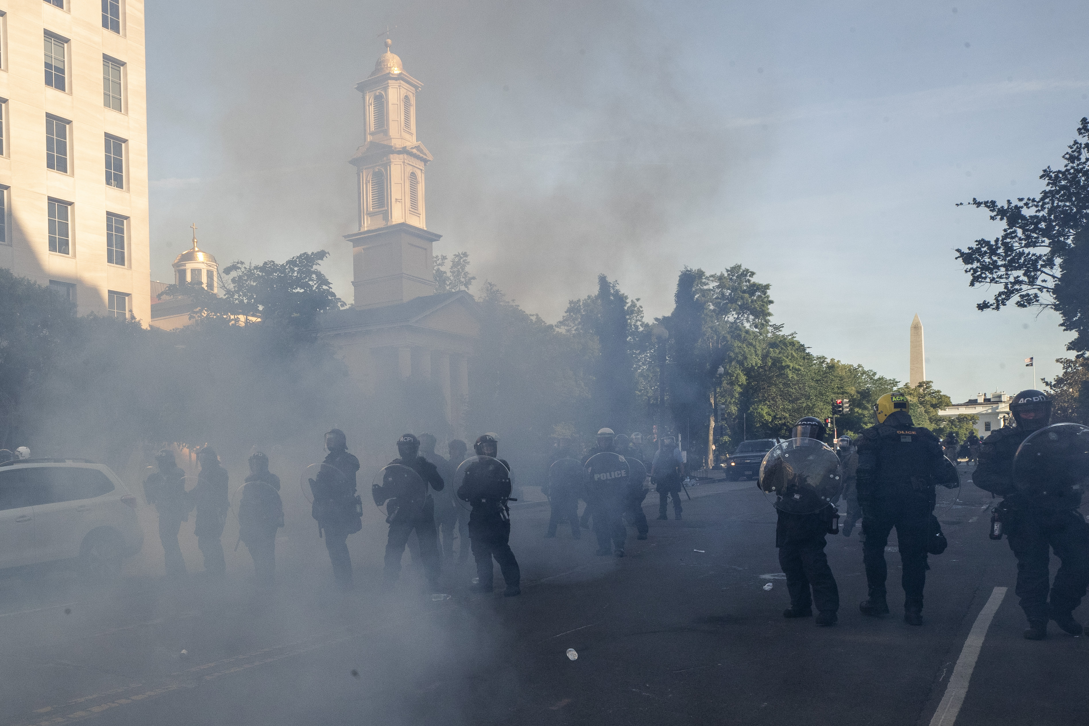 Tear gas floats in the air as a line of police move demonstrators away from St. John's Church across Lafayette Park from the White House, as they gather to protest the death of George Floyd, Monday, June 1, 2020, in Washington.