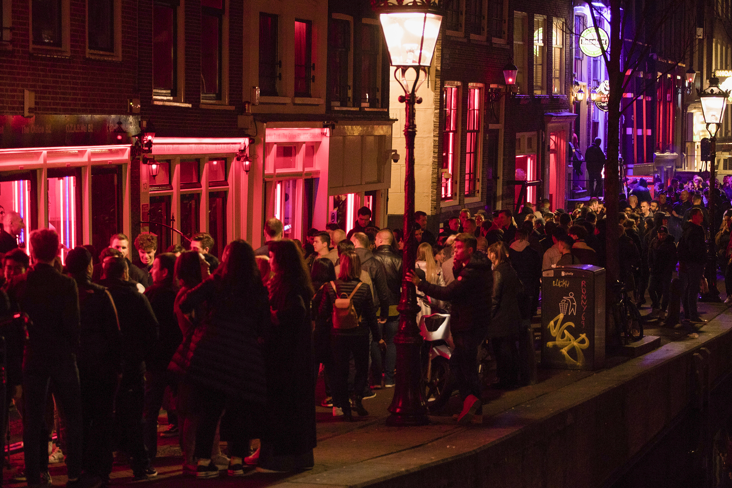 Tourists bathing in a red glow emanating from peep show windows are packed shoulder to shoulder as they shuffle through the alleys in Amsterdam's red light district, Netherlands on March 29, 2019. (Peter Dejong—AP)