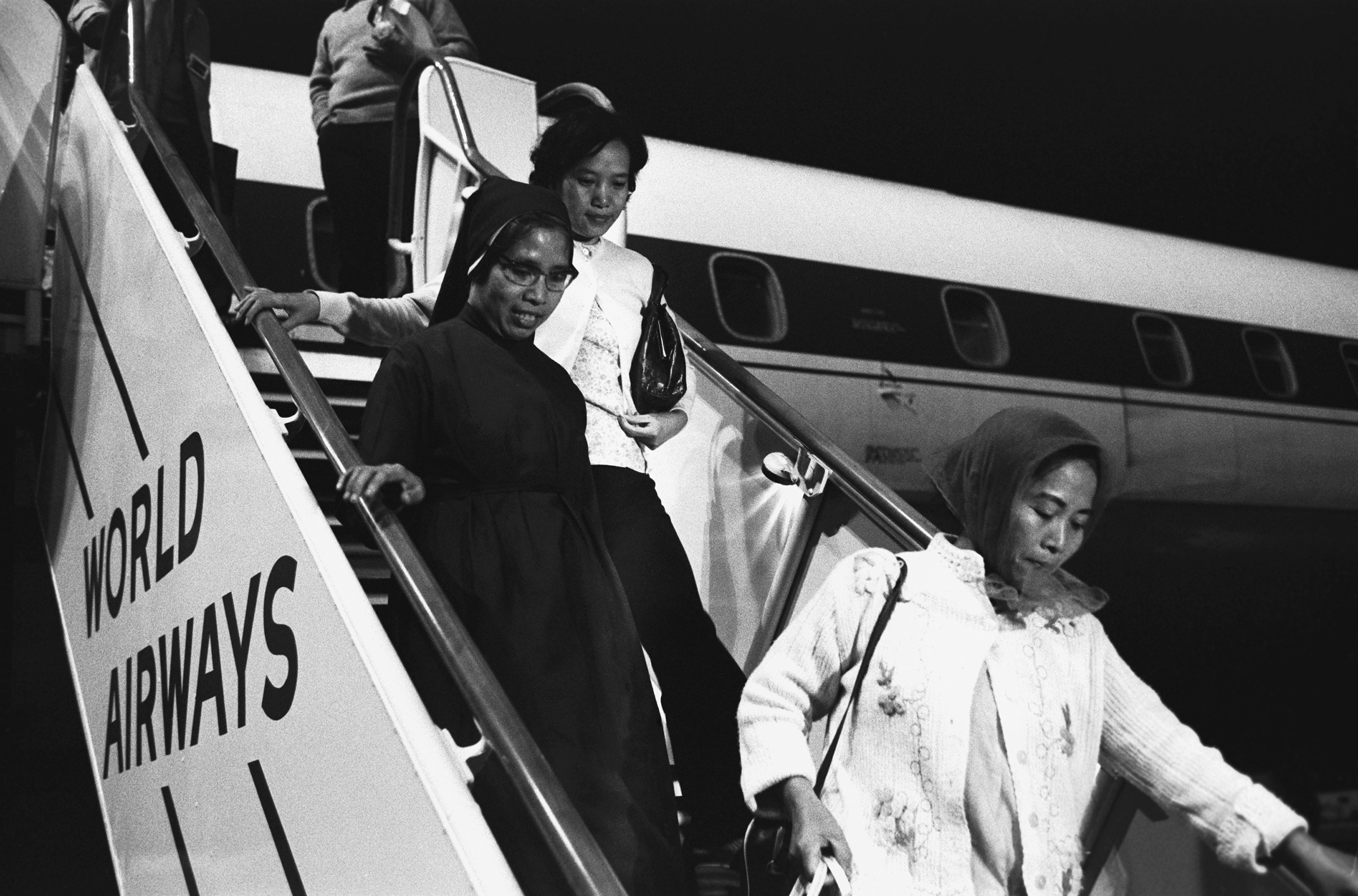 Refugees from Vietnam descend a flight of stairs from an airplane in Oakland, California, April 1975