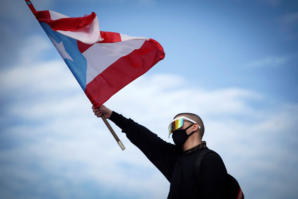 Puerto Rican reggaeton singer Bad Bunny waves a Puerto Rican flag as he takes part of a demonstration demanding Governor Ricardo Rossello's resignation in San Juan, Puerto Rico on July 17, 2019. (AFP via Getty Images)