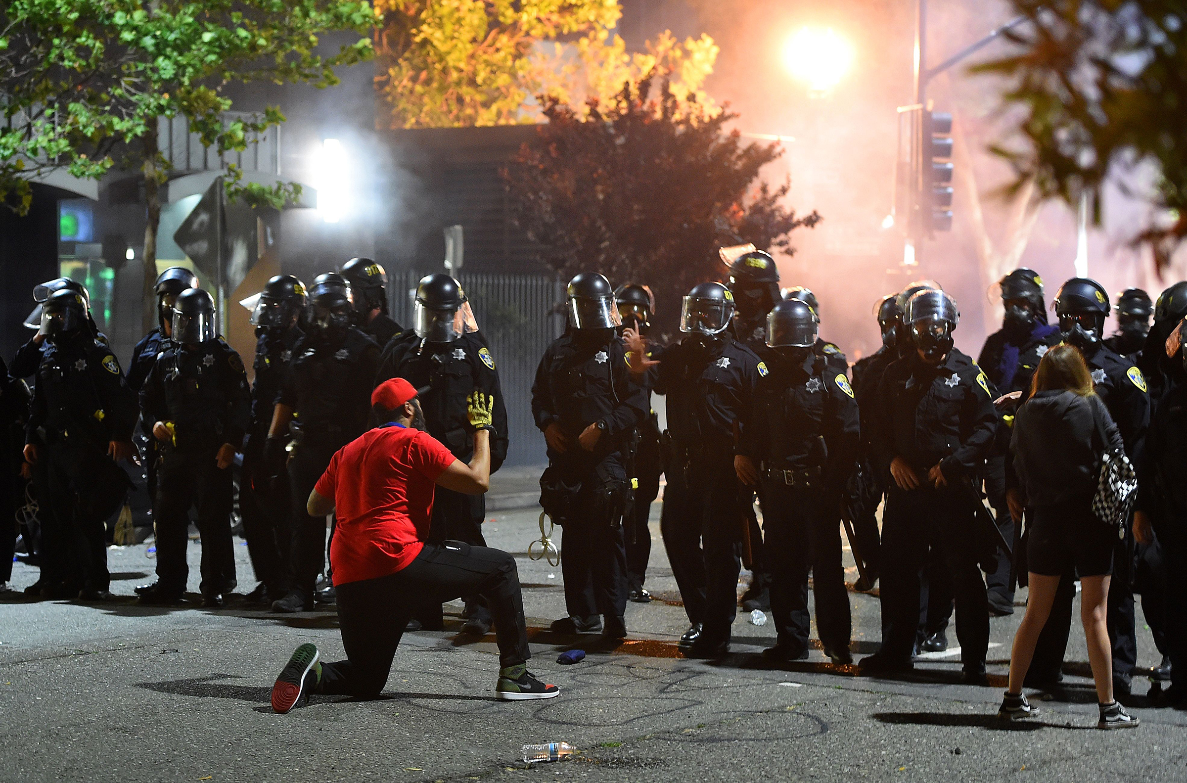 A man kneels in front of a police skirmish line in Oakland California on May 29, 2020. (Josh Edelson—AFP via Getty Images)