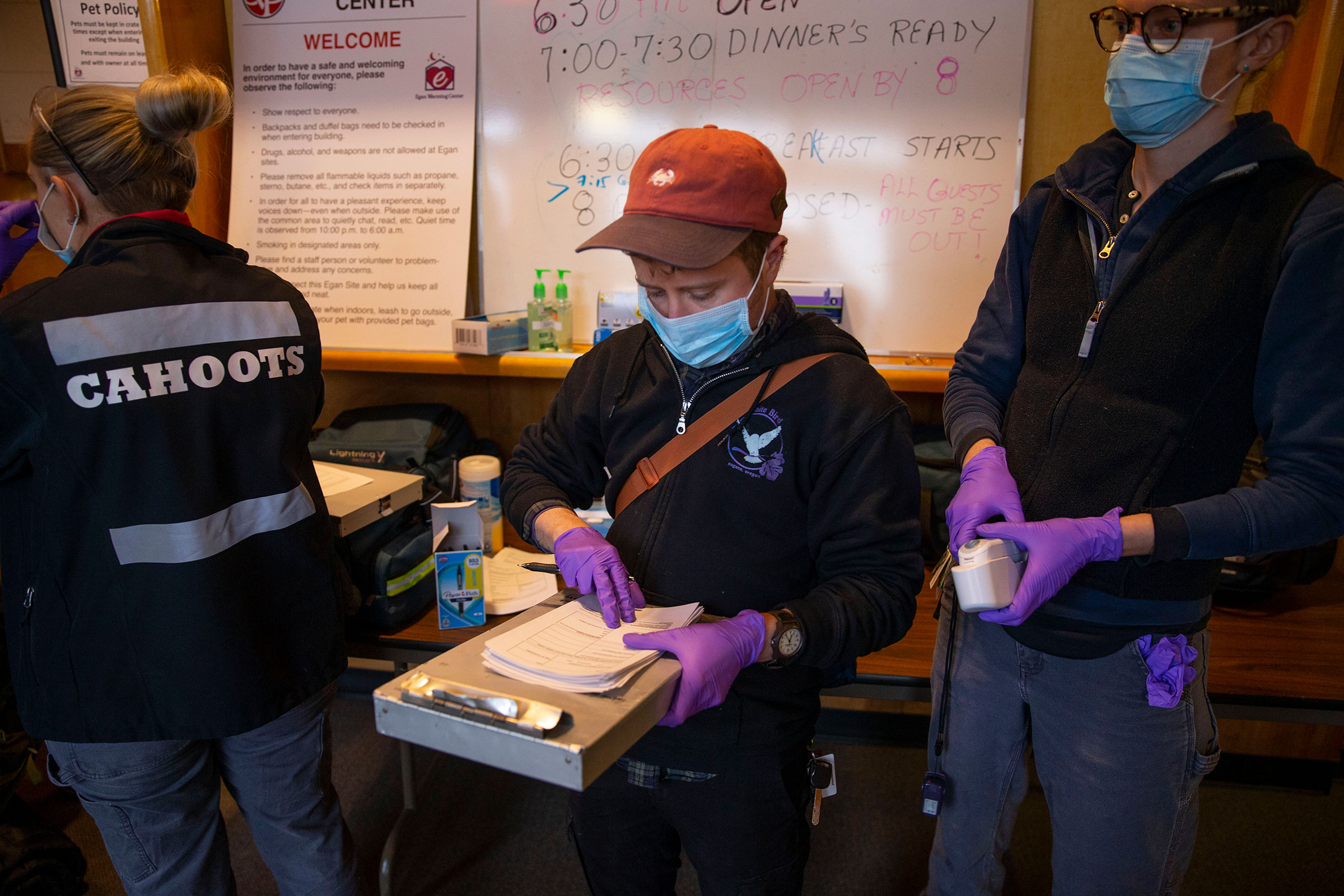an EMT with CAHOOTS, joins a team from White Bird in screening guests for health concerns at the Egan Warming Center in Springfield, Ore.