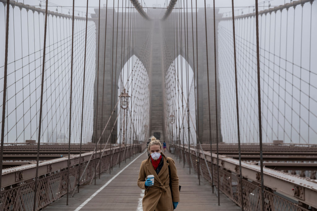 A woman wearing a mask walks the Brooklyn Bridge in the midst of the coronavirus (COVID-19) outbreak  on March 20, 2020 in New York City. (Victor J. Blue — Getty Images)