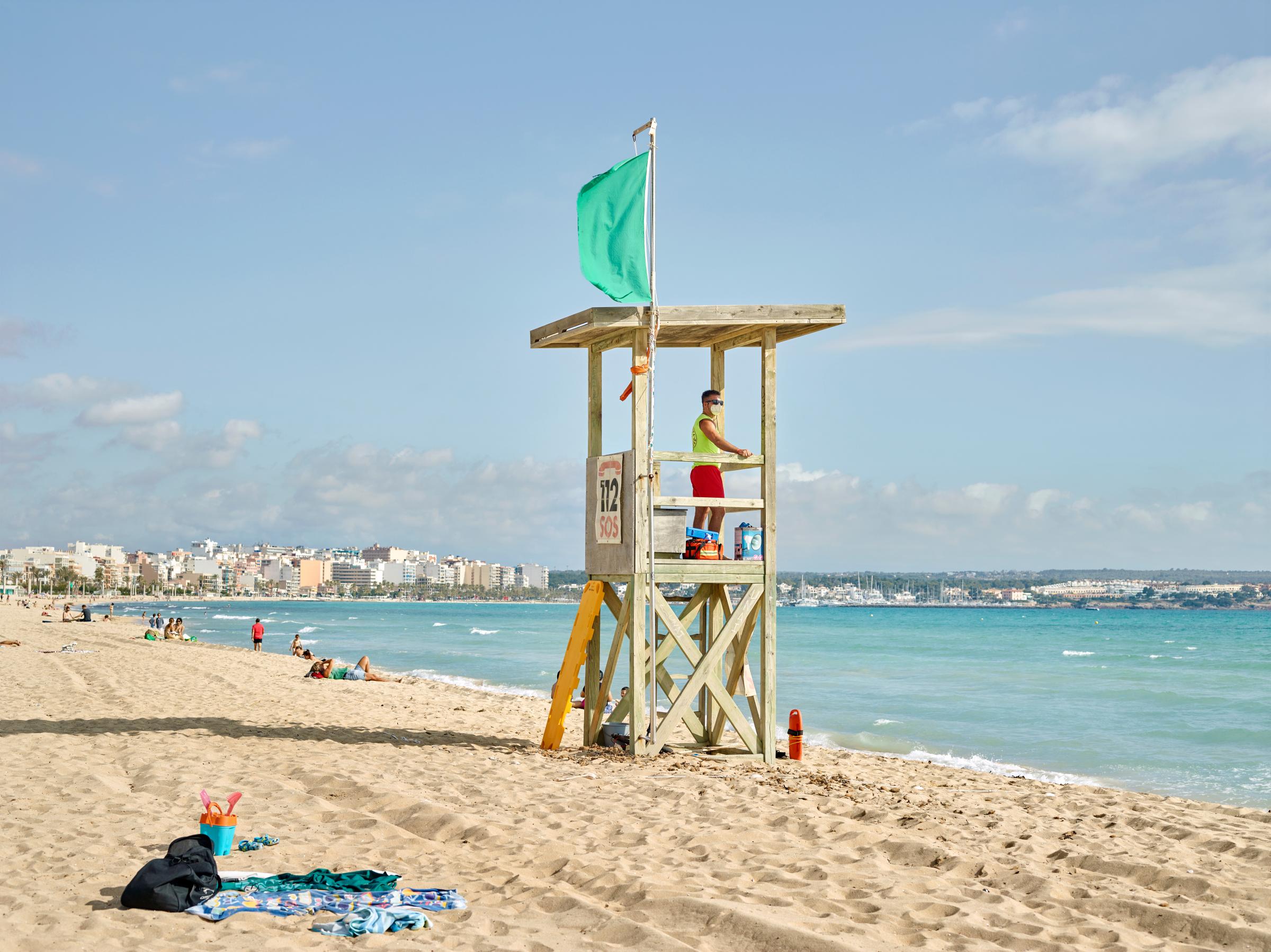 Mallorca , view of the Playa de Palma beach with the lifeguard wearing the mask for safety reasons.
