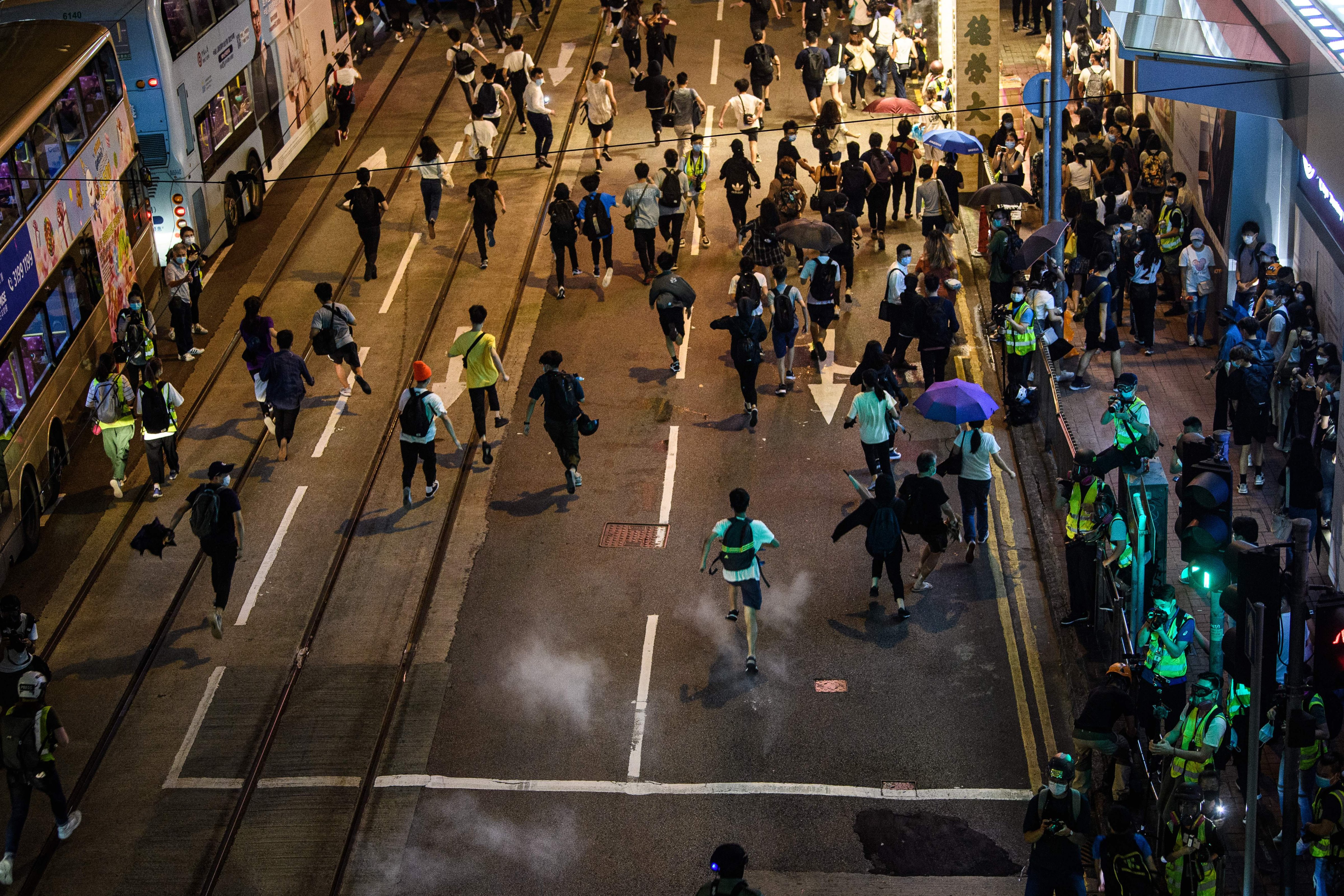 Pro-democracy protesters run as police fire pepper ball rounds to disperse the crowd in the Central district of Hong Kong on June 9, 2020, as the city marks the one-year anniversary since pro-democracy protests erupted (ANTHONY WALLACE/AFP via Getty Images)