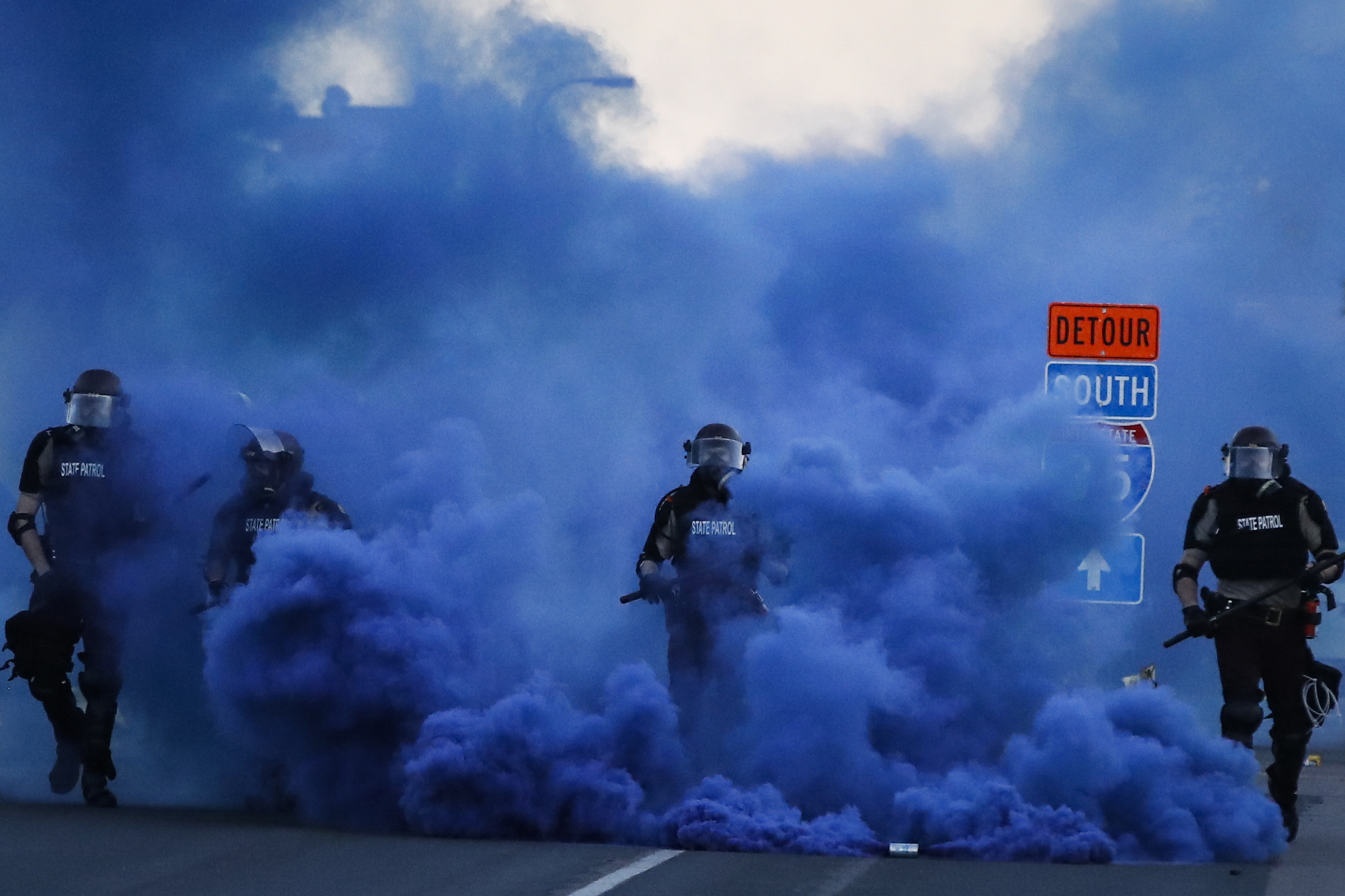 Police in riot gear walk through a cloud of blue smoke as they advance on protesters near the Minneapolis 5th Precinct, on May 30, 2020. (John Minchillo—AP)