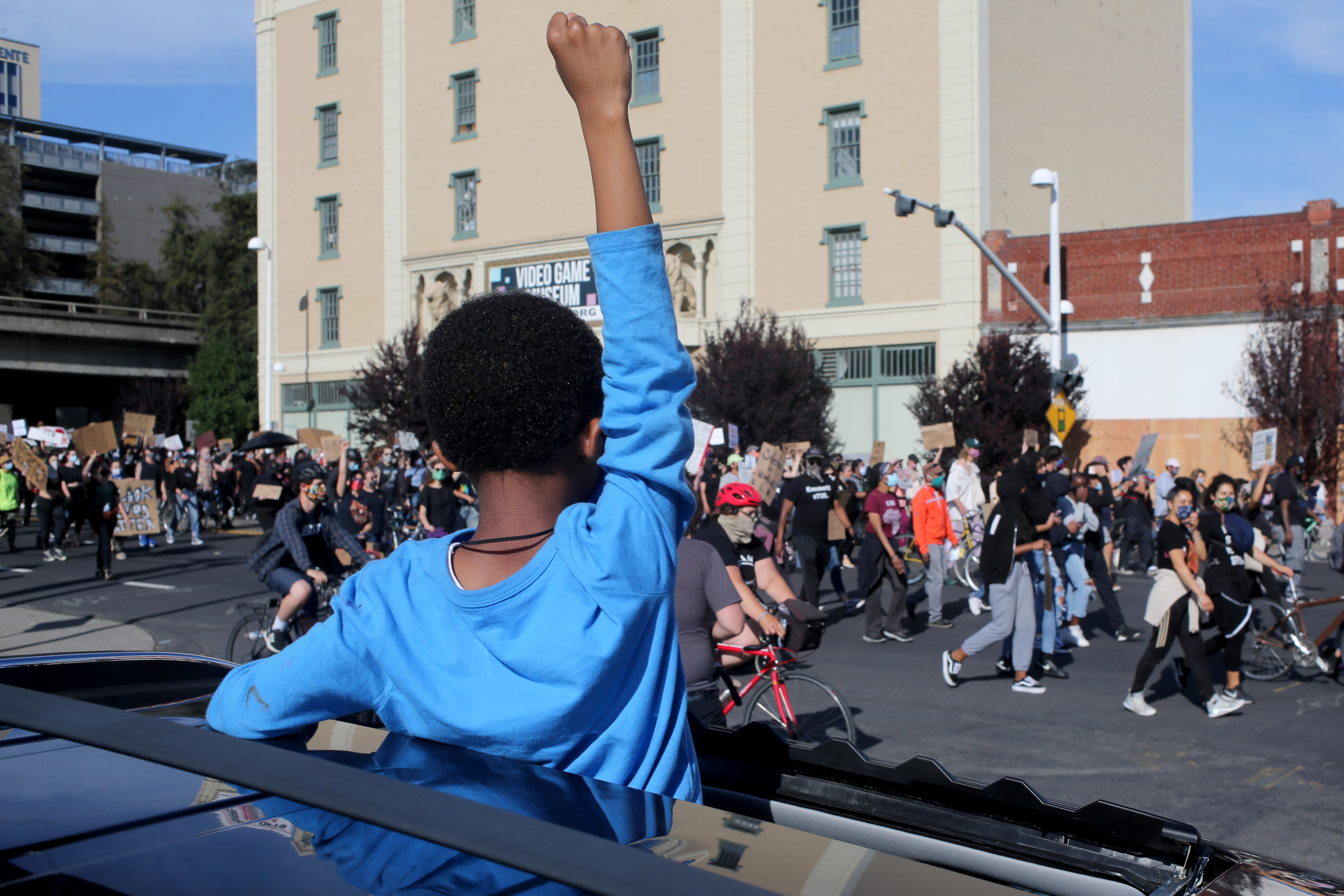 Douglas Briscoe raises his fist from the sunroof of his father's SUV as thousands of protesters march in Oakland, Calif., on June 1, 2020 over the death of George Floyd. (Ray Chavez—East Bay Times/Getty Images)