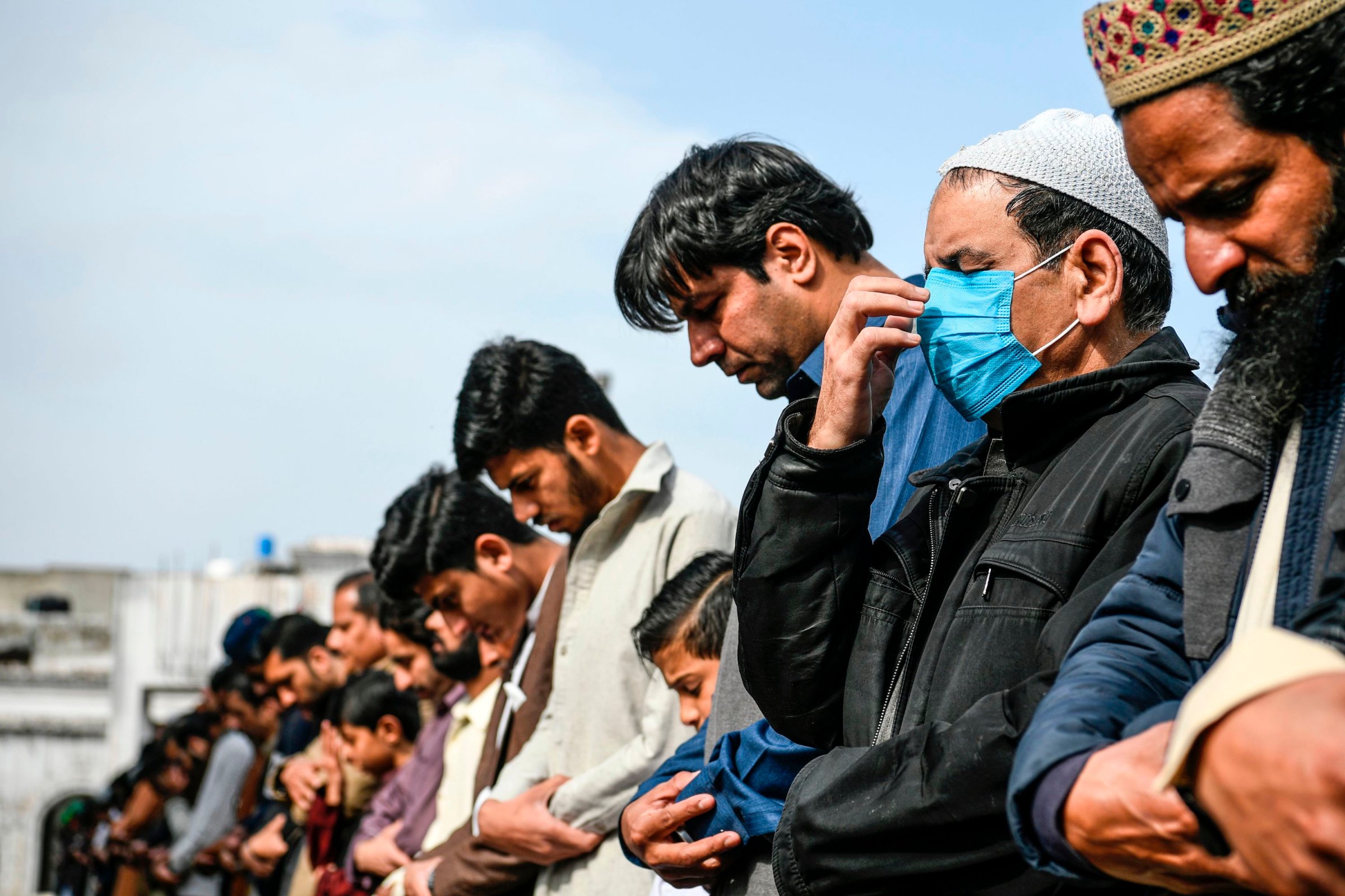 A resident (R) wearing a facemask as a preventive measure against the spread of the COVID-19 coronavirus offers Friday prayers along with other Muslims at a mosque in Rawalpindi on March 13, 2020.