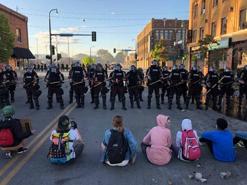 People sit on the street in front of a row of police officers during a rally in Minneapolis on May 29 after the death of George Floyd.
