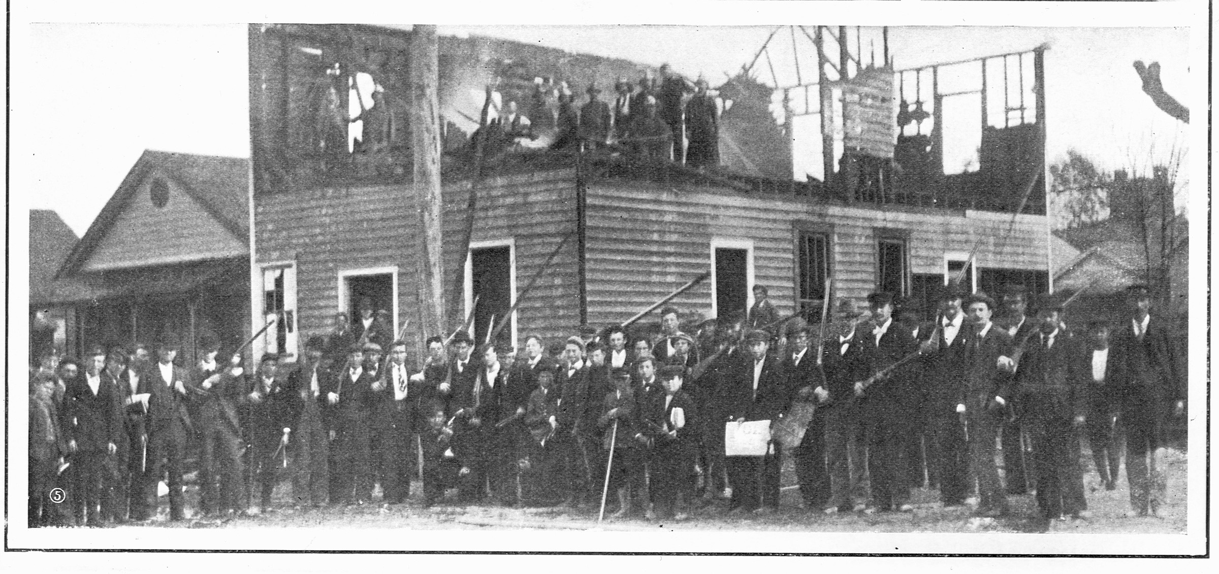 Men gather outside the charred remains of The Daily Record after the 1898  race riots in Wilmington, North Carolina. (Library of Congress)
