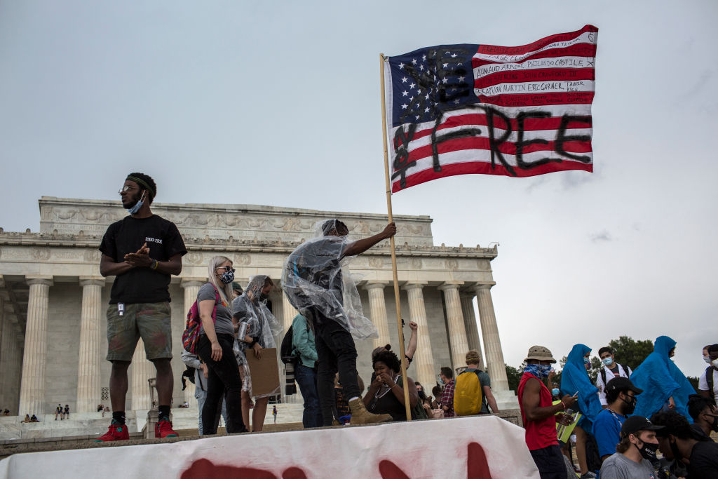 A man waves an American flag with the words 'Not Free' painted on it as he takes part in a Juneteenth march and rally in front of the Lincoln Memorial on June 19, 2020. (Probal Rashid—Getty Images)