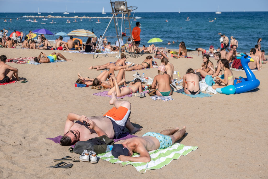 People are seen sunbathing at the Barceloneta beach during