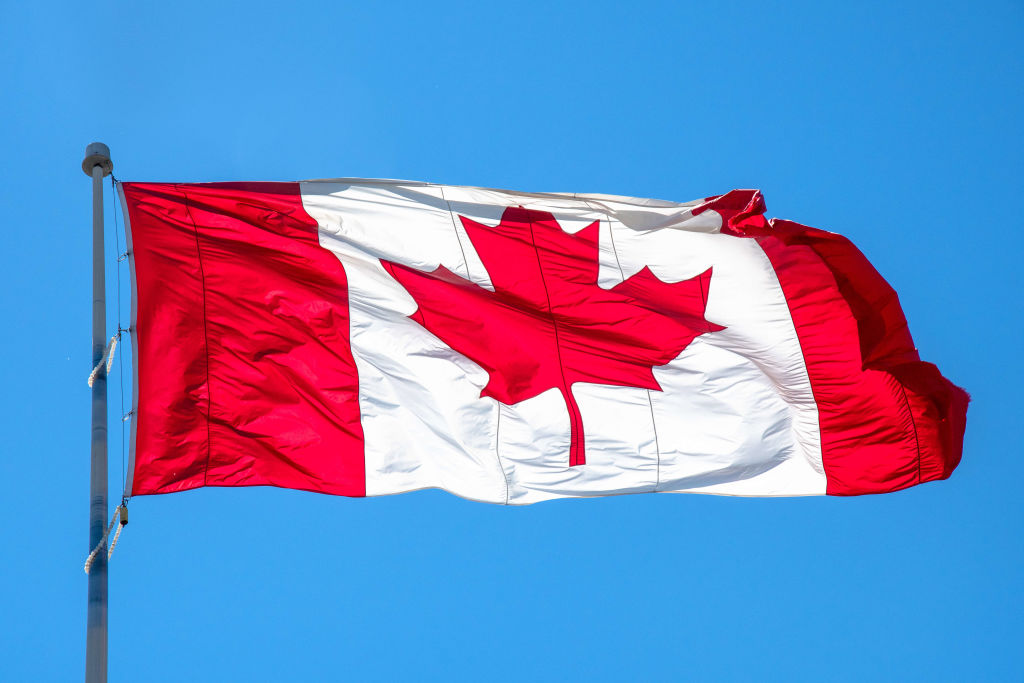 Flag of Canada or Canadian flag waving on blue clear sky