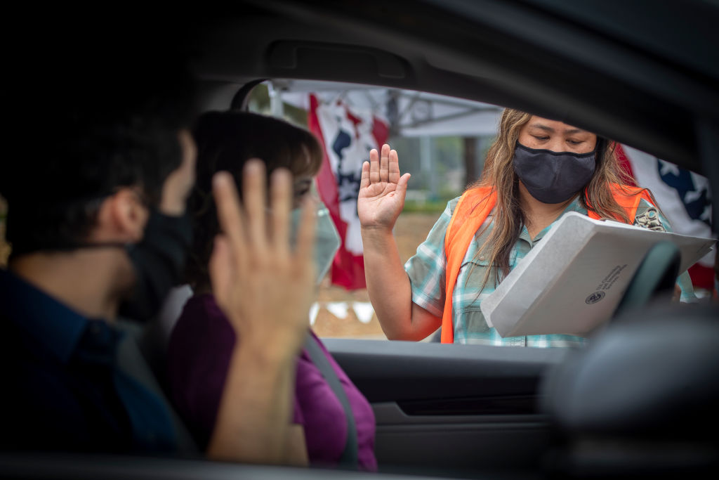 U.S. Citizenship and Immigration Services officer Rochelle Reyes, right, administers the oath of allegiance to Brian Gebel, left, during a drive through citizenship naturalization in Laguna Niguel, California, on June 23, 2020. (Allen J. Schaben—Los Angeles Times/Getty Images)