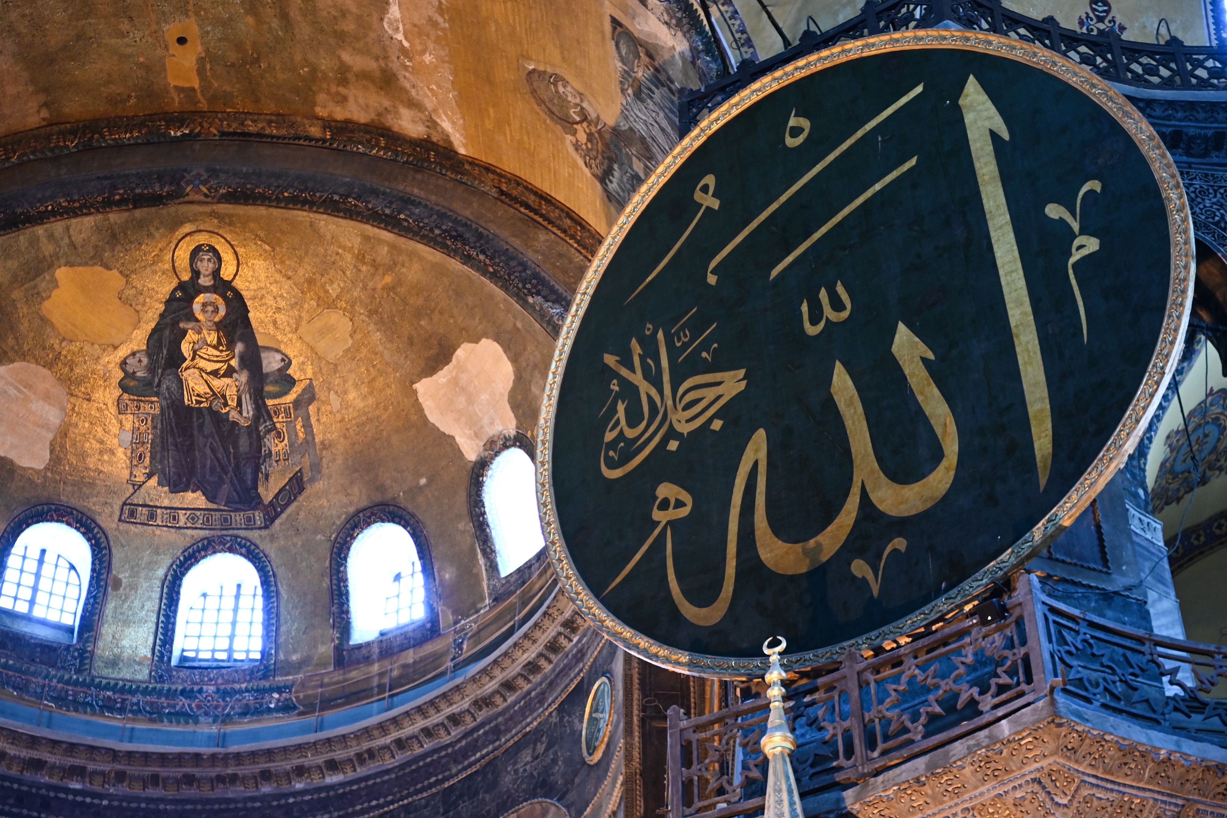 This picture taken on July 2, 2020 shows the Virgin Mary and child fresco (L) and a calligraphic Roundel with Arabic letters bearing the name of Allah and other Muslim prophets hanging on the dome of the Hagia Sophia museum, in Istanbul, Turkey. (Ozan Kose—AFP/Getty Images)