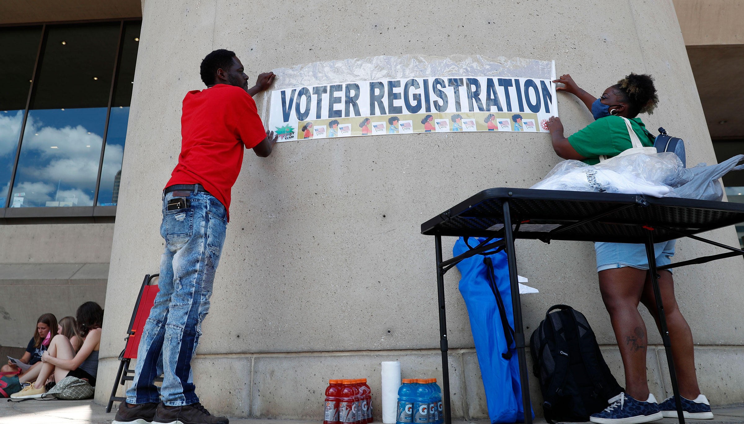 Aetry Jones, left, and Caerry Rigbon tape up a voter registration sign on Dallas City Hall before a Juneteenth 2020 celebration and protest against police brutality in Dallas, on June 19, 2020. (LM Otero—AP)