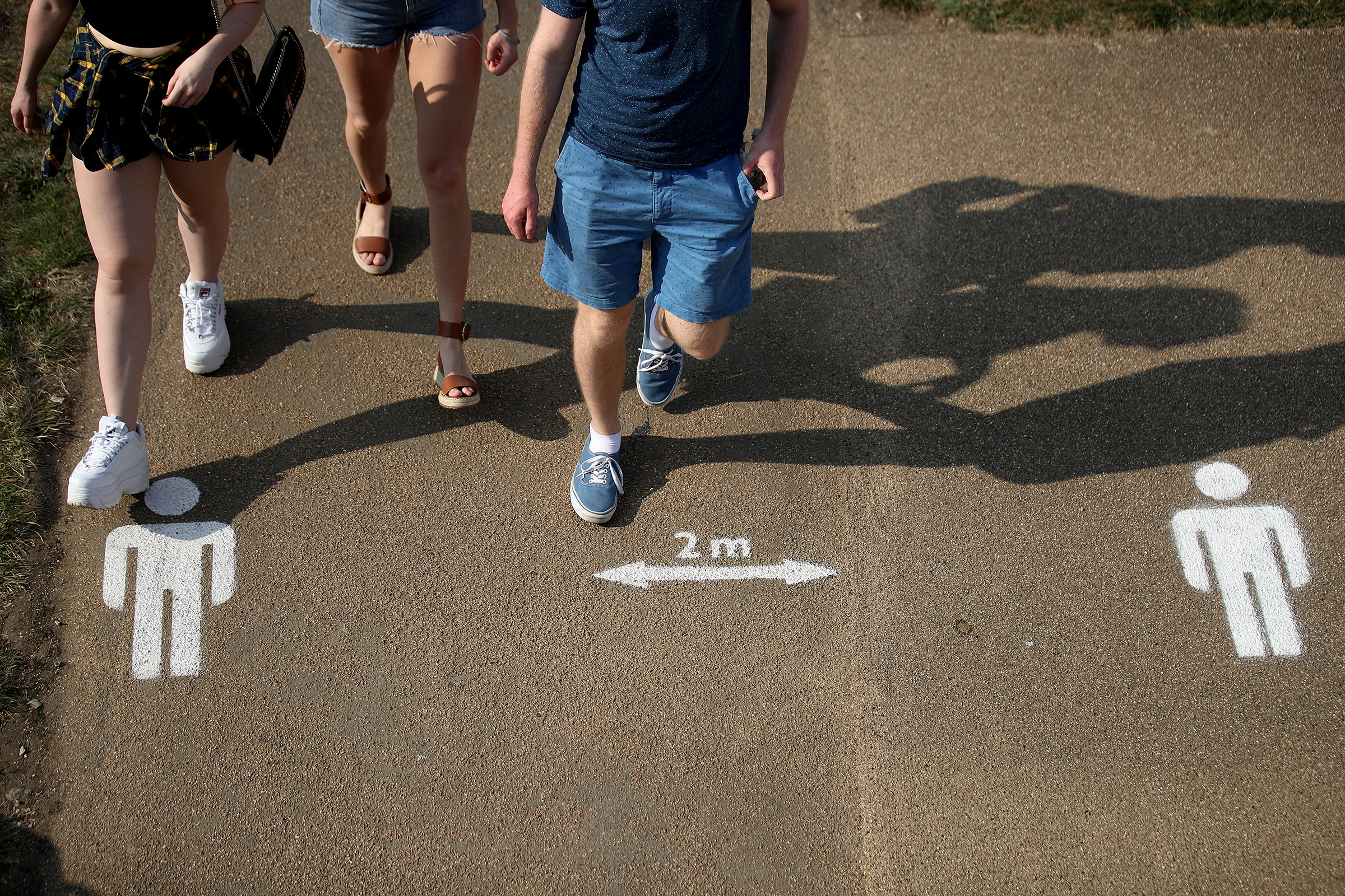 People walk past the social distancing markings on the ground at Queen Elizabeth Olympic Park in London, England on April 11, 2020. (Alex Pantling—Getty Images)