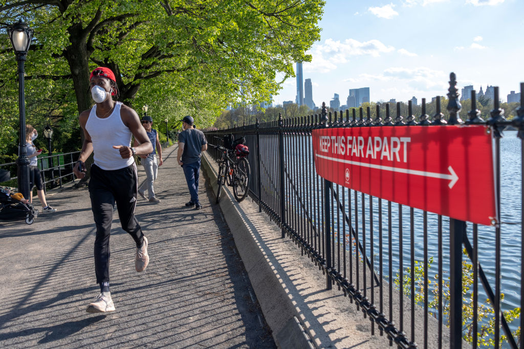 A man wearing a mask runs near a sign that says, "Keep this far apart" in Central Park in New York City on May 3, 2020. (Getty Images&mdash;2020 Alexi Rosenfeld)