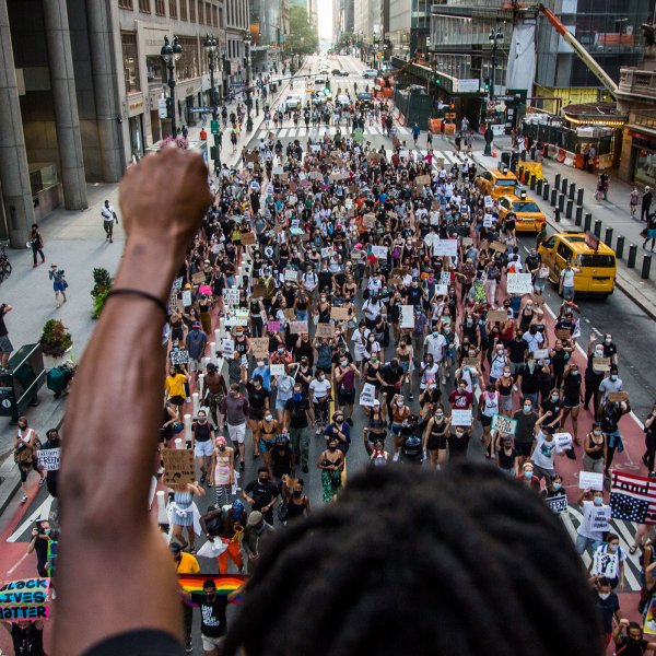A man raises his arm in support of the crowd of protesters marching in downtown New York, NY on July 26, 2020.