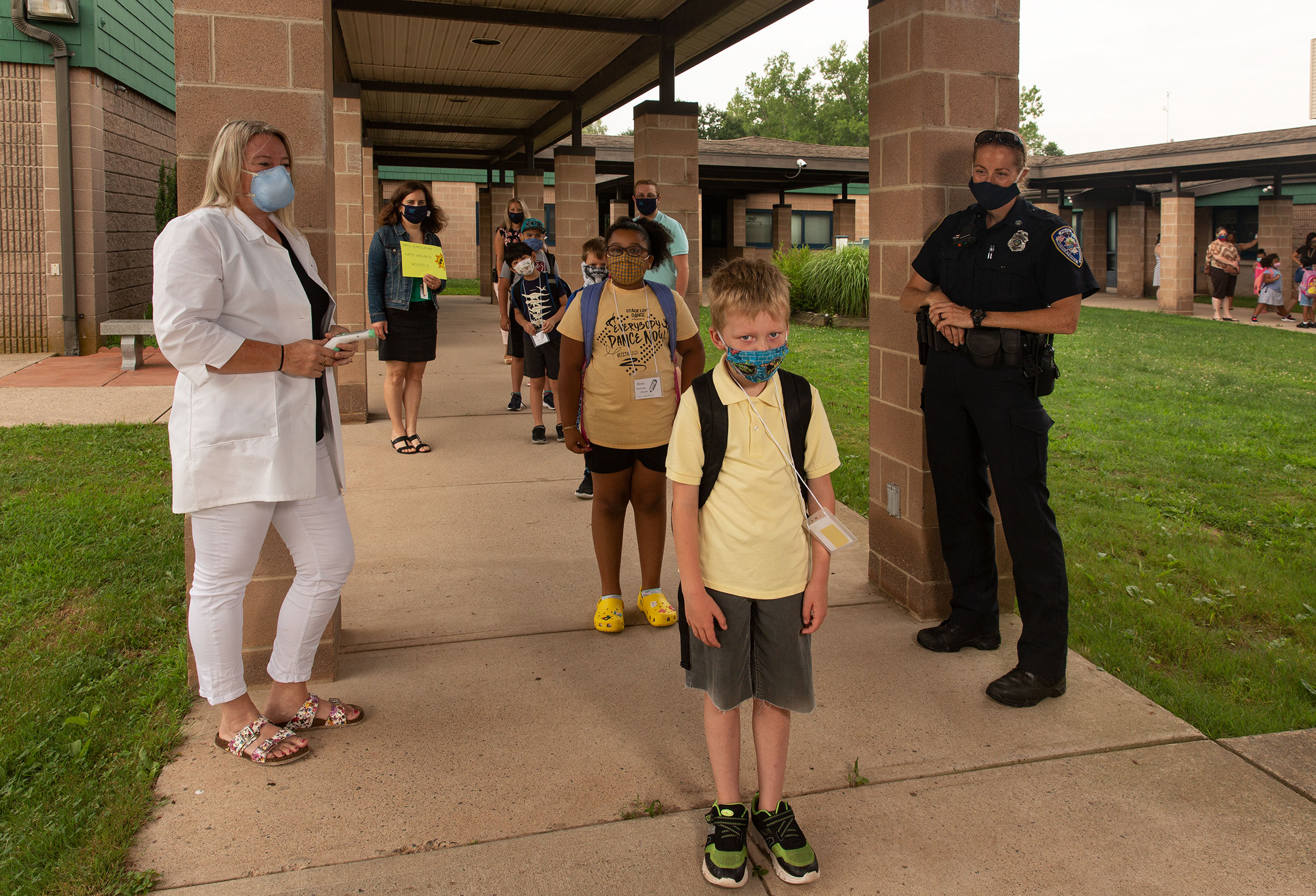 Nurse Sarah Ladd and school resource officer Kristen Tyrseck ensure kids keep a safe distance apart as they enter Wesley Elementary School 
                    in Middletown, Conn. (Photographs by Gillian Laub for TIME)