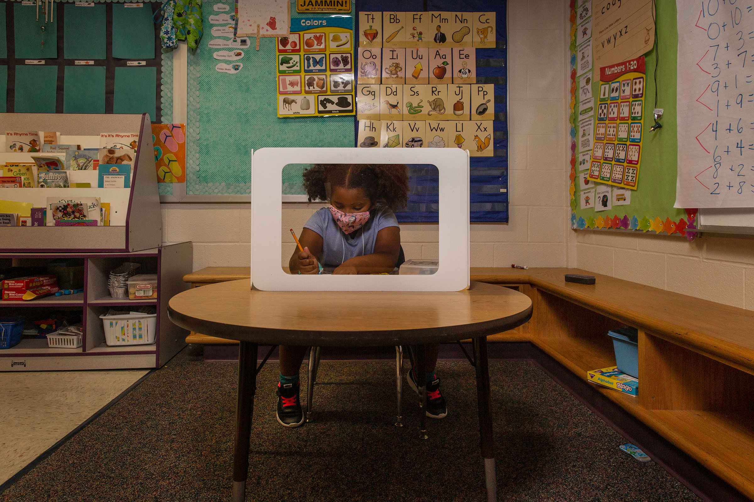 Plastic shields surround the desk where 6-year-old Aven Mullins works (Gillian Laub for TIME)