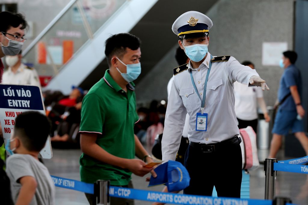 A staff member from Vietnam's Centre of Disease Control assists passengers wearing face masks as they queue up for temperature checks at the departures terminal at Danang's international airport on July 27, 2020. (Hoang Khanh–AFP/Getty Images)