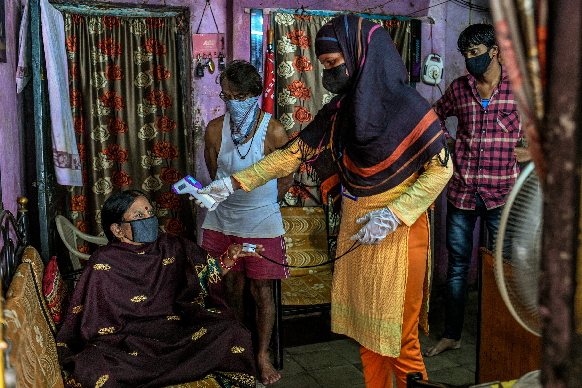 Un trabajador de la salud controla la temperatura y los niveles de oxígeno de una mujer en el barrio pobre de Dhole Patil el 10 de agosto.