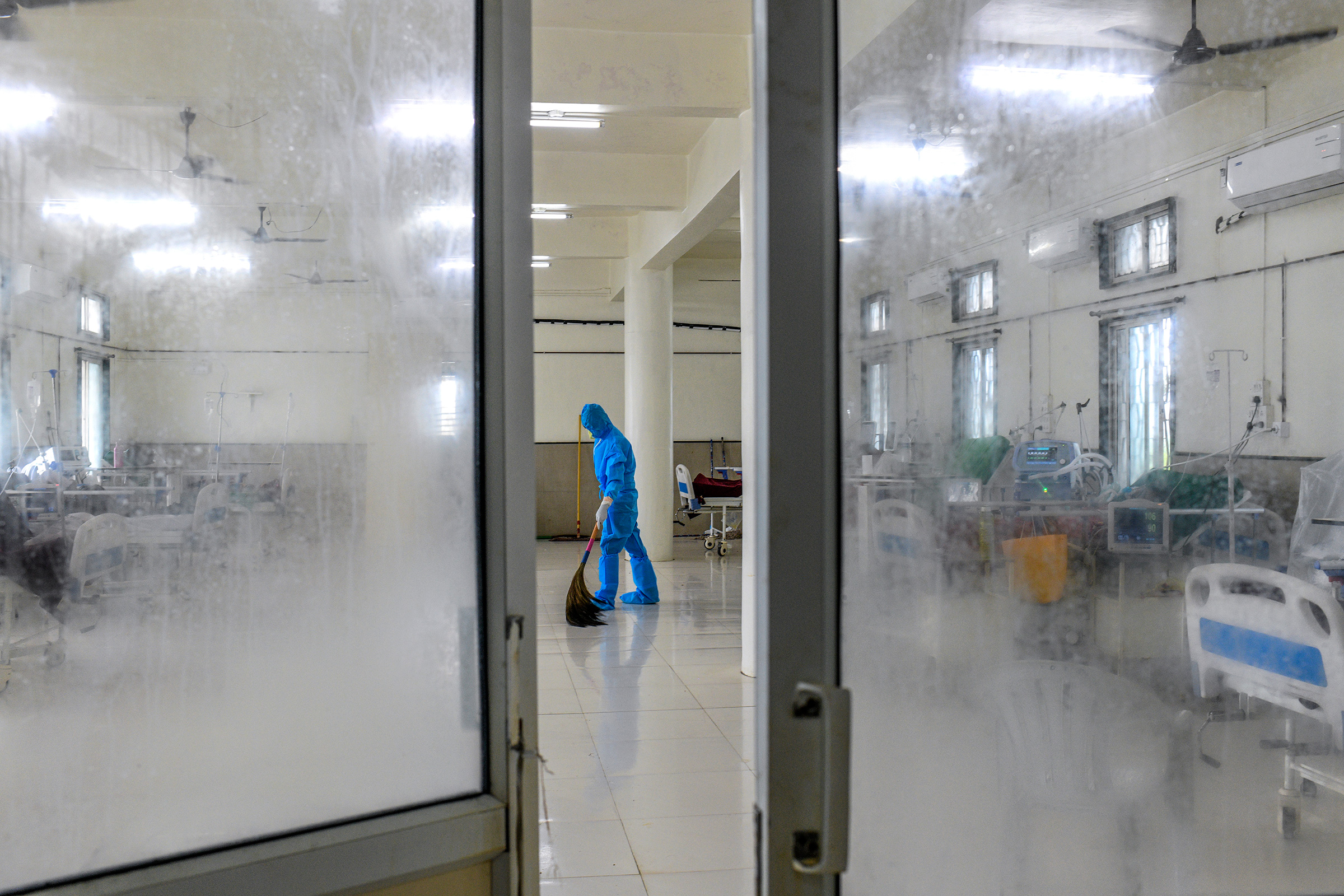 A young worker dressed in personal protective equipment sweeps the floor of the intensive-care unit. (Atul Loke for TIME)